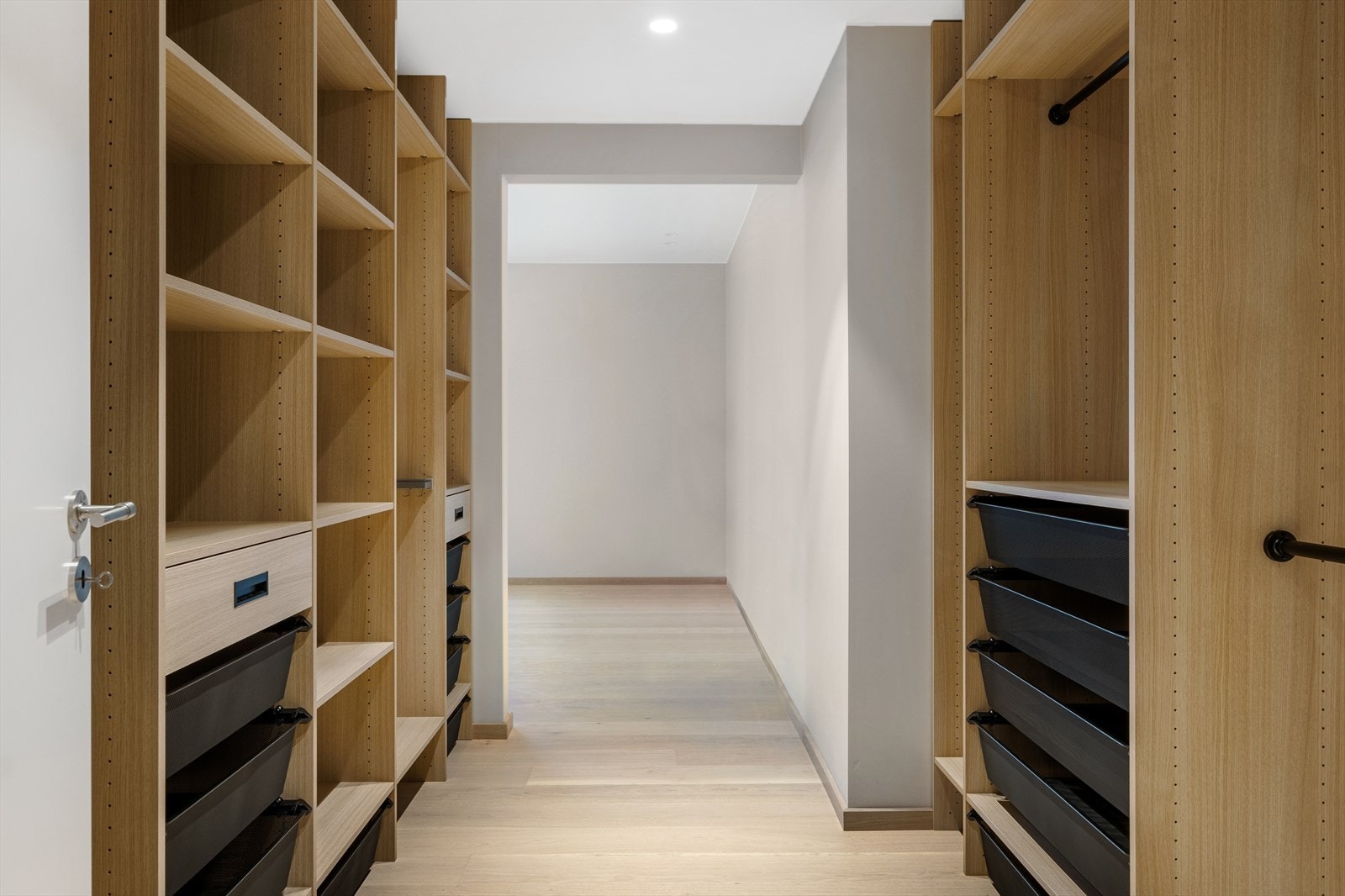 Walk-in garderoben med hovedsoverom i bakgrunnen, sett fra gangen. Garderoben har fått innredning fra Langlo Galleribilde