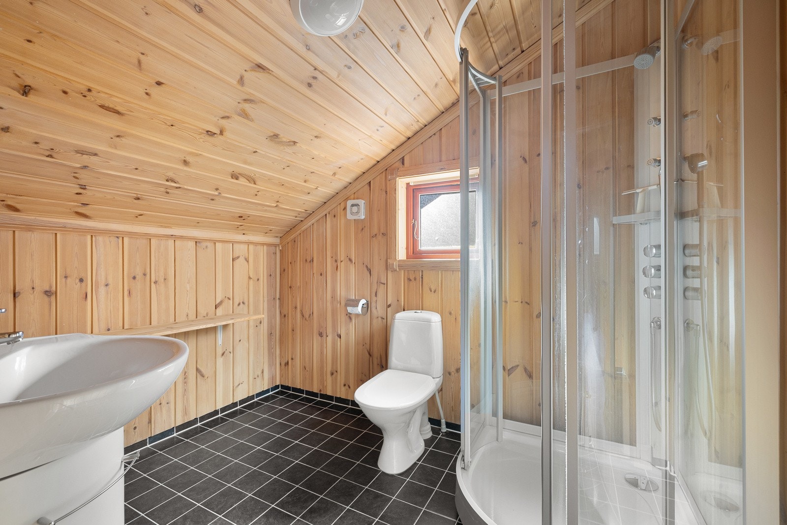 Badet på loftet har flislagt gulv med elektriske varmekabler, vegger og himling kledd med trepanel. Rommet er innredet med nedfelt servant, toalett og dusjkabinett. Galleribilde