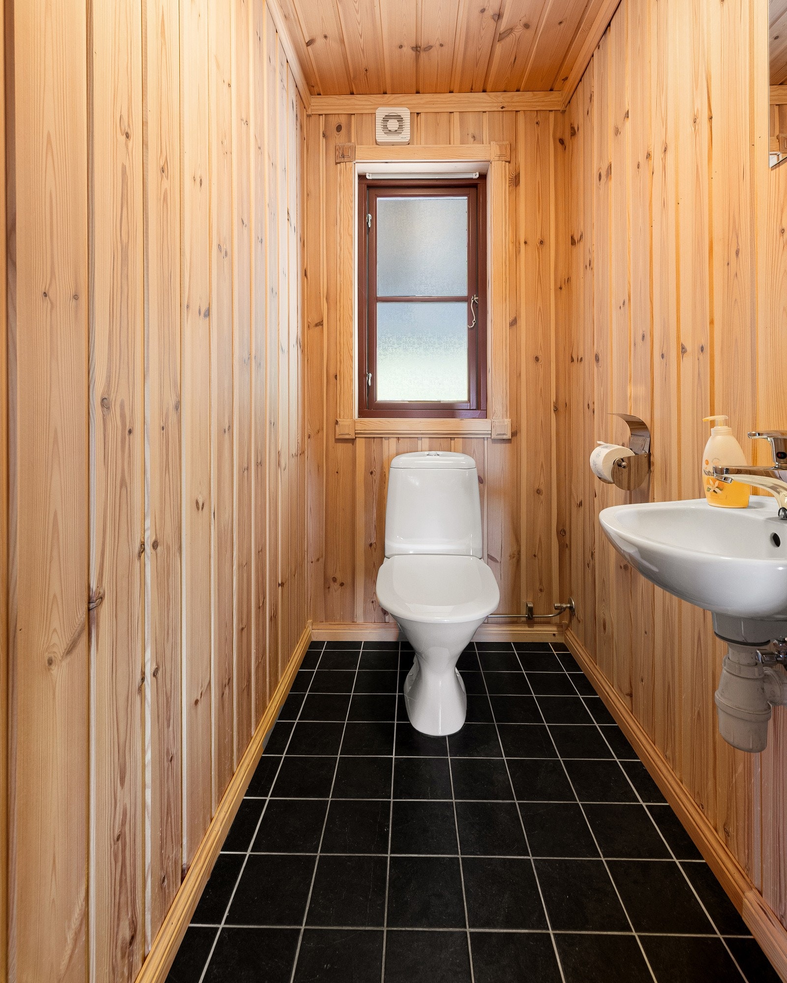 Toalettrommet har flislagt gulv, mens både vegger og himling er kledd med trepanel. Rommet er utstyrt med servant og toalett. Galleribilde