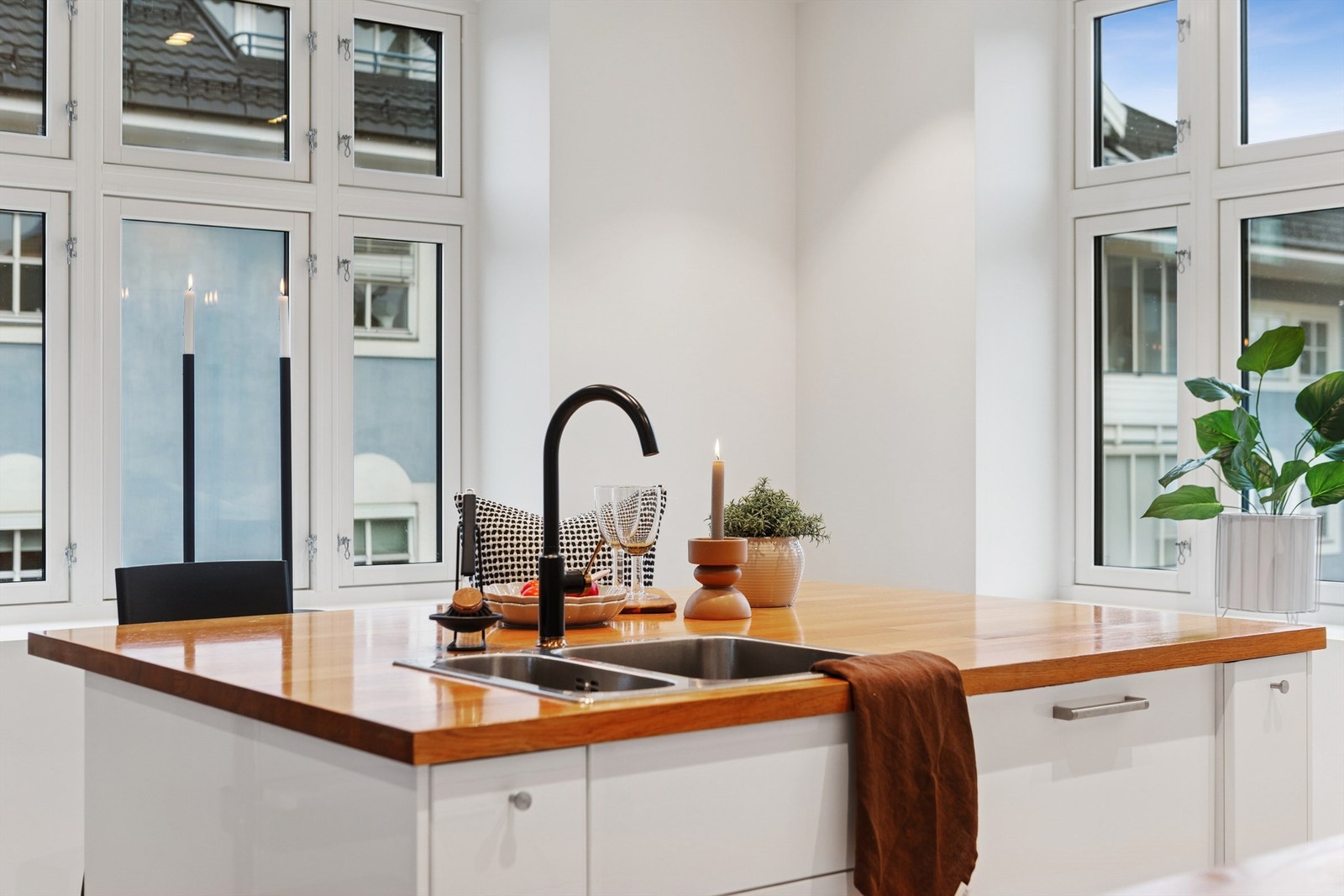 Moderne kjøkkeninnredning med slette, hvite fronter og benkeplate i heltre. Galleribilde