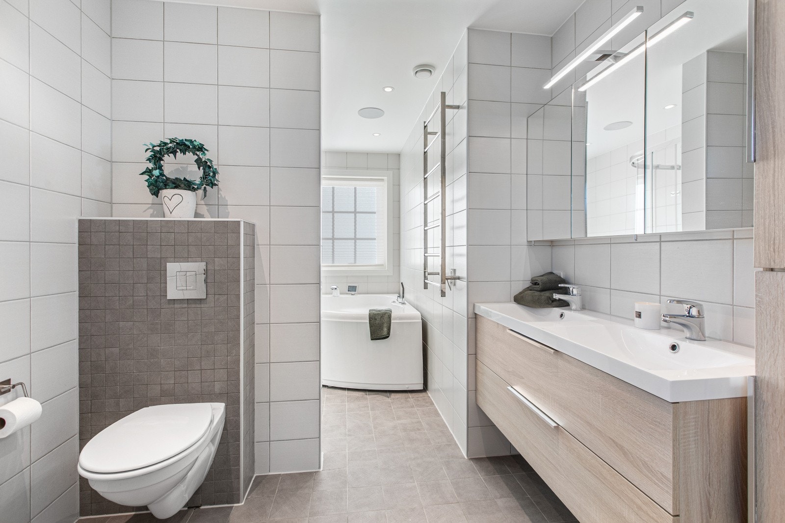 Rommet har fliser på veggene, downlights i himlingen og grå fliser på gulv med gulvvarme. Galleribilde