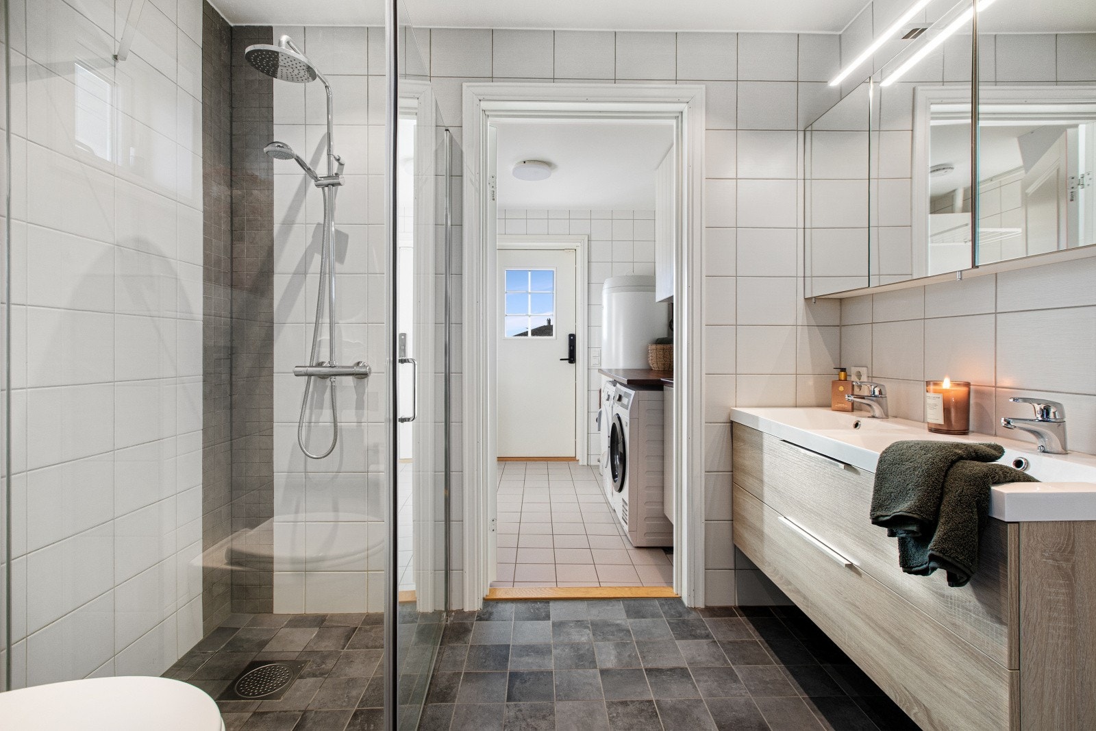 Badet er utstyrt med dobbel servant, overskap med speil, skuffeseksjon, dusjnisje og klosett. Galleribilde