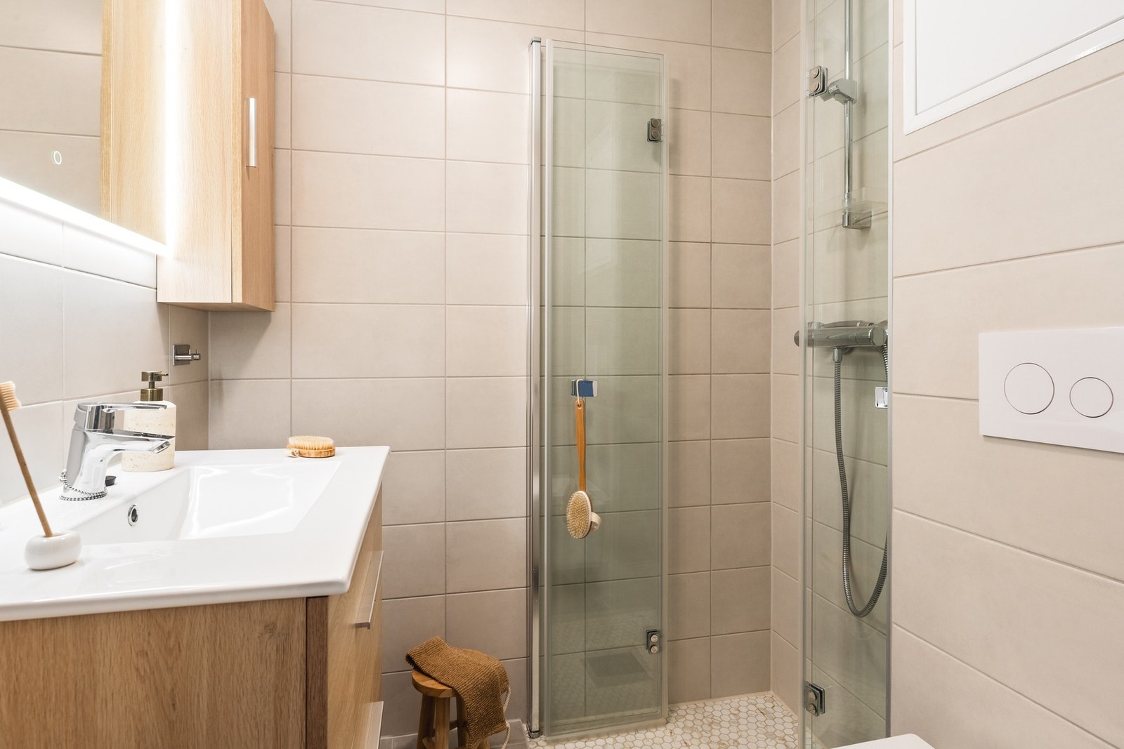 Delikat helfliset bad med varme i gulv. Badet er innredet med vegghengt toalett, servant med innredning, veggskap og dusjhjørne. Galleribilde