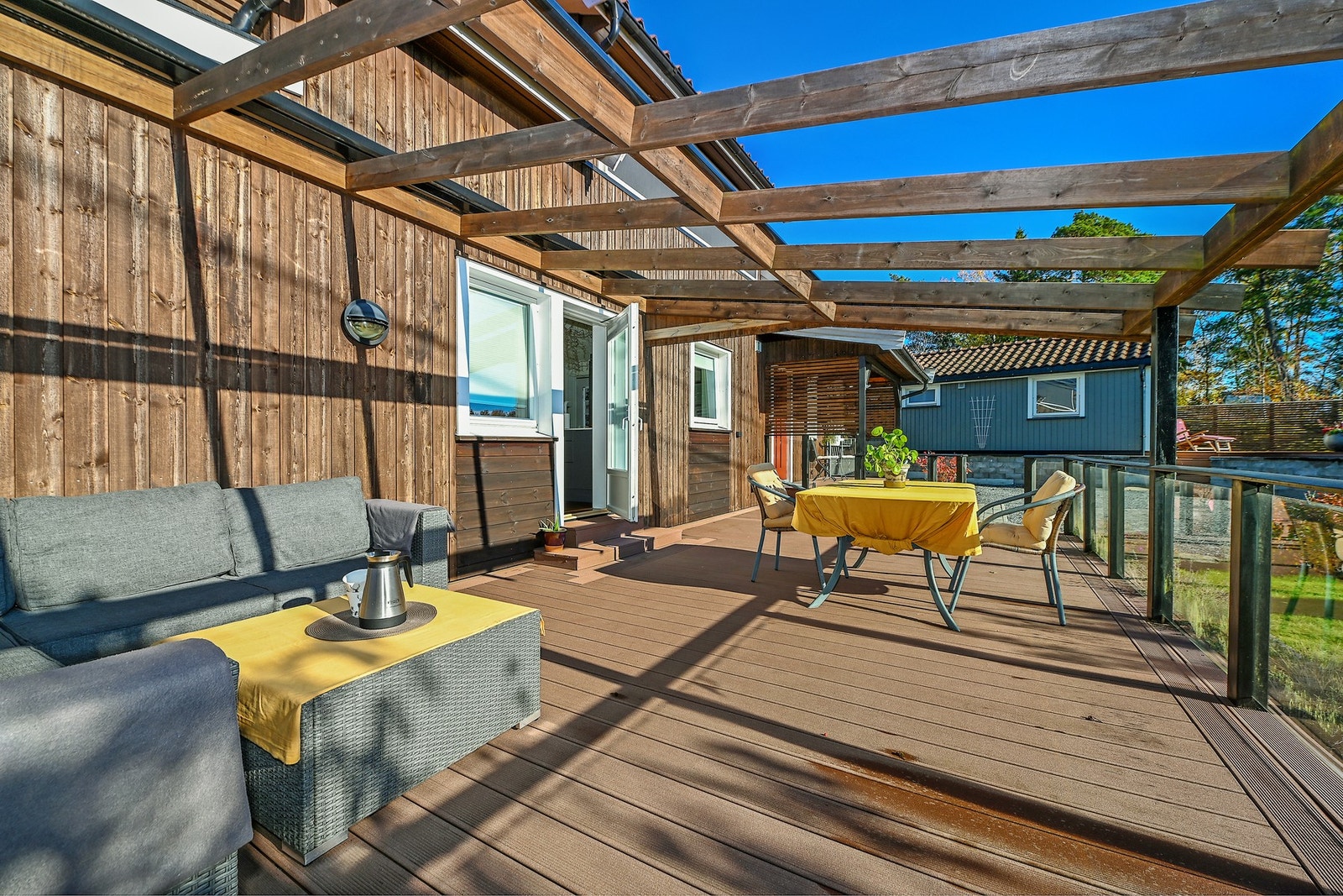 Stor terrasse med pergola, og over denne er det markise som er festet i skinner. Galleribilde