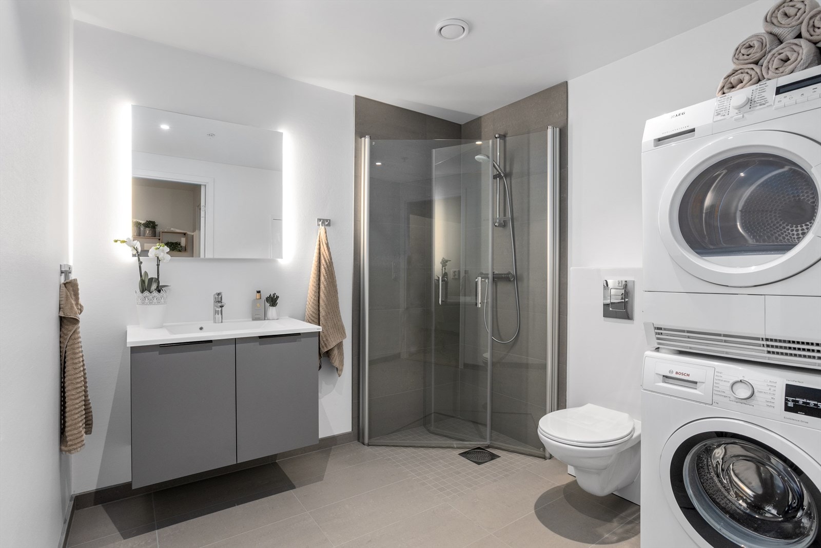 Moderne baderomsinnredning med nedfelt servant, veggmontert toalett, dusjvegger/hjørne og varmekabler. Galleribilde