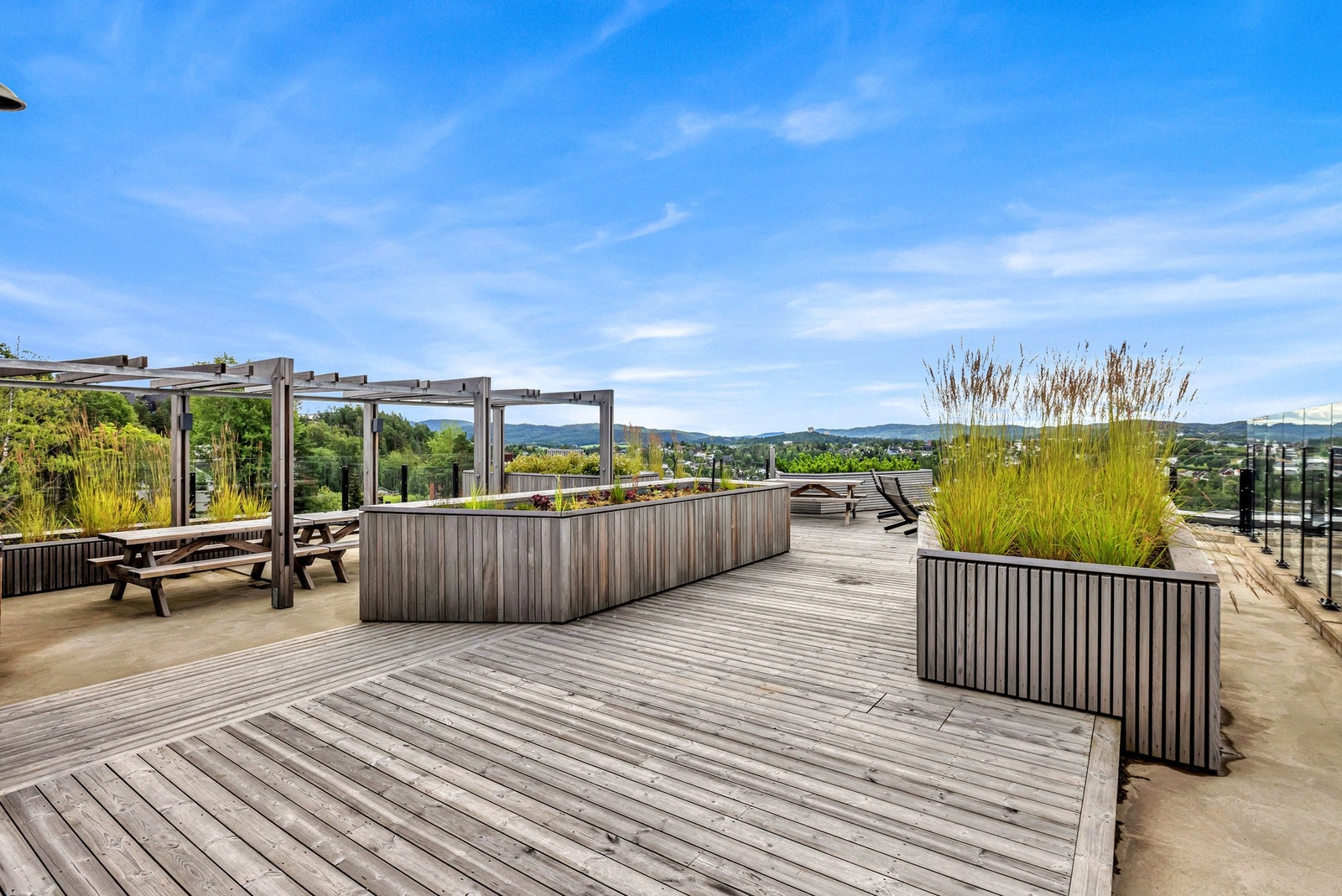 Grønn beplantning, blomsterkasser, pergola og solsenger for å nevne noe. Galleribilde