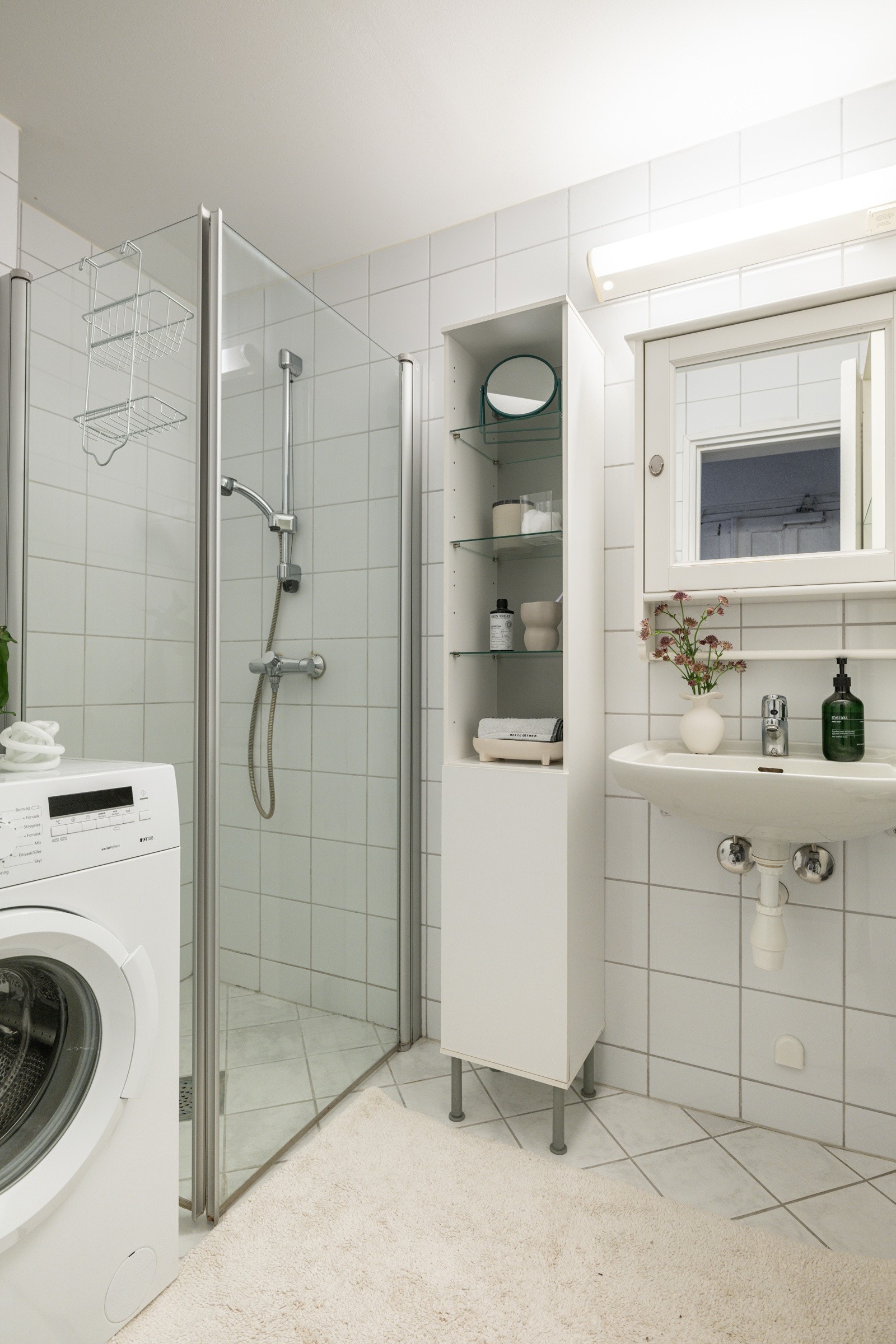 Baderommet er utstyrt med vegghengt servant, speilskap med belysning over, høyskap, dusjhjørne med glassdører og opplegg for vaskemaskin. Galleribilde