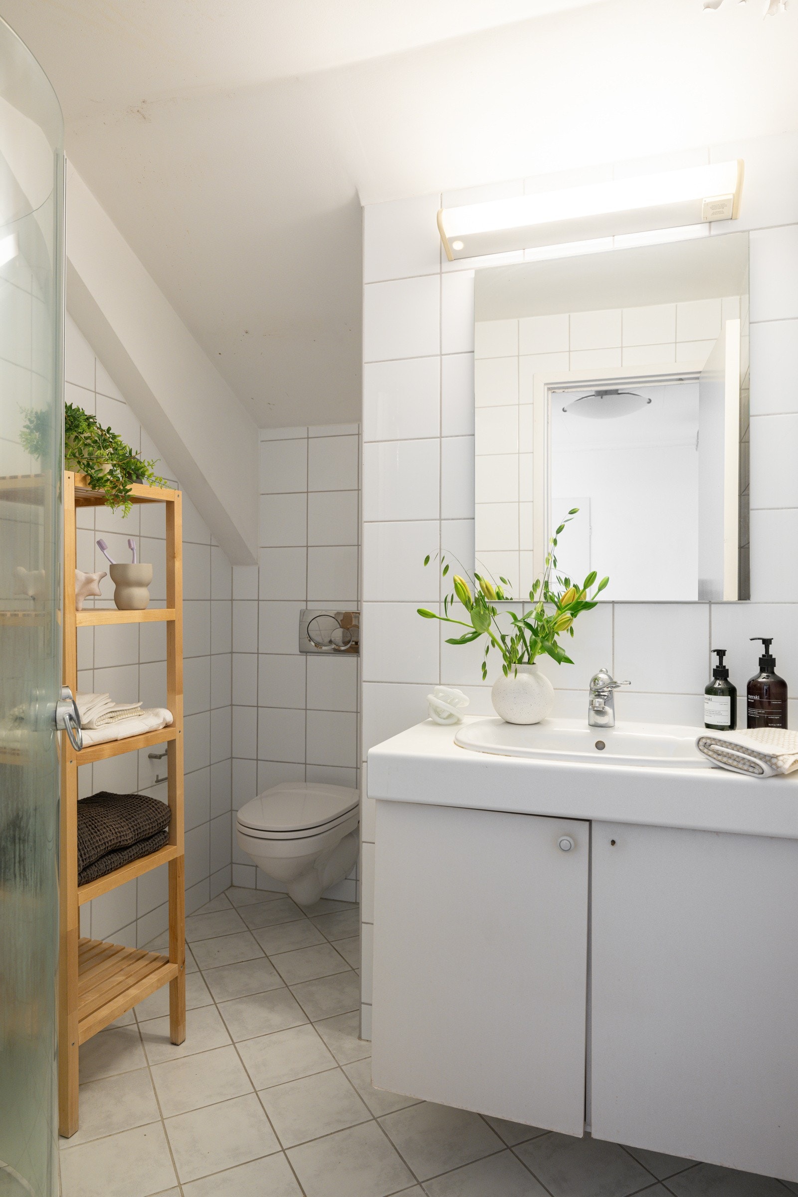 Baderommet i loftsetasjen er utstyrt med servantskap, speil med belysning over, dusjhjørne med glassdører og vegghengt toalett. Galleribilde