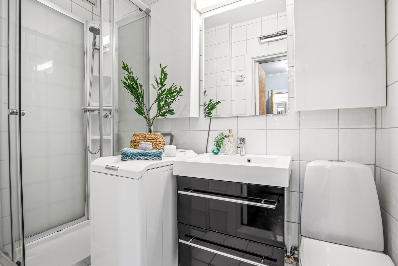 Badet er utstyrt med flislagte gulv og vegger, samt en innredning med glatte, folierte fronter og en heldekkende servant Galleribilde