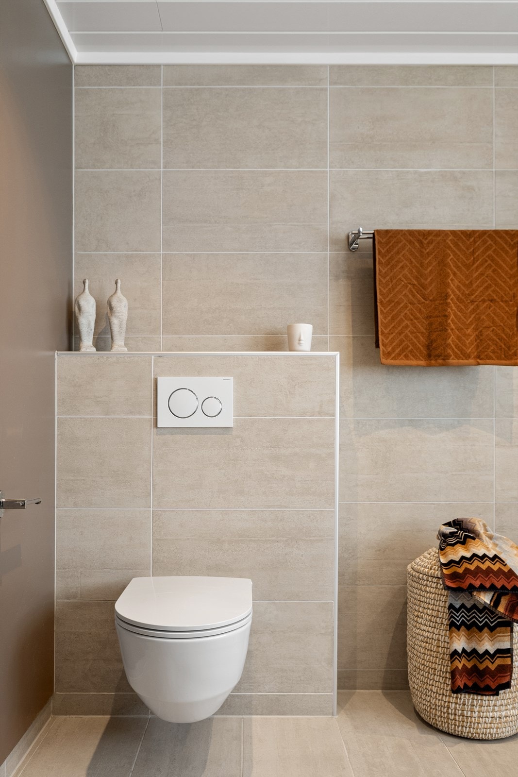 Badet har veggmontert toalett med innebygget sisterne. Galleribilde