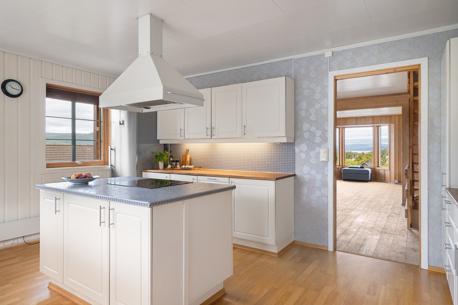 Pen kjøkkeninnredning med malte og profilerte fronter. Heltre benkeplate med nedfelt vaskekum. Flislagt benkeplate for kjøkkenøy med nedfelt induksjonstopp.Pen kjøkkeninnredning med malte og profilerte fronter. Heltre benkeplate med nedfelt vaskekum. Galleribilde