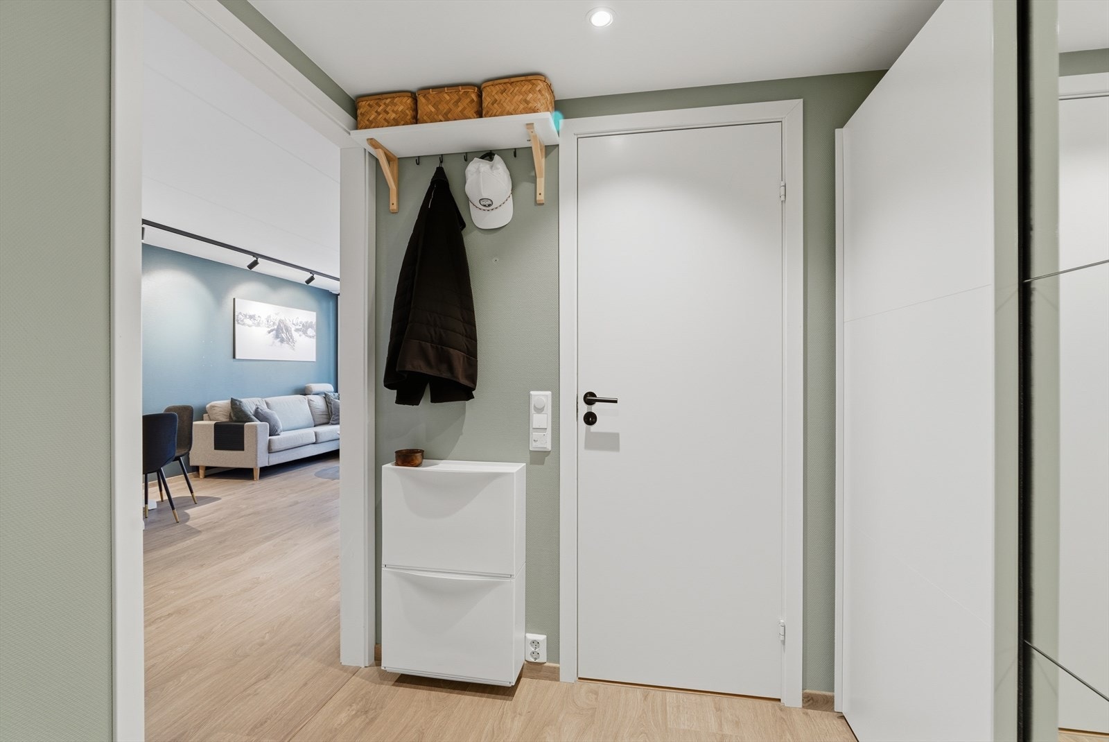 Vi blir ønsket velkommen inn i en lys entré med fine fargevalg og en romslig skyvedørsgarderobe. Galleribilde
