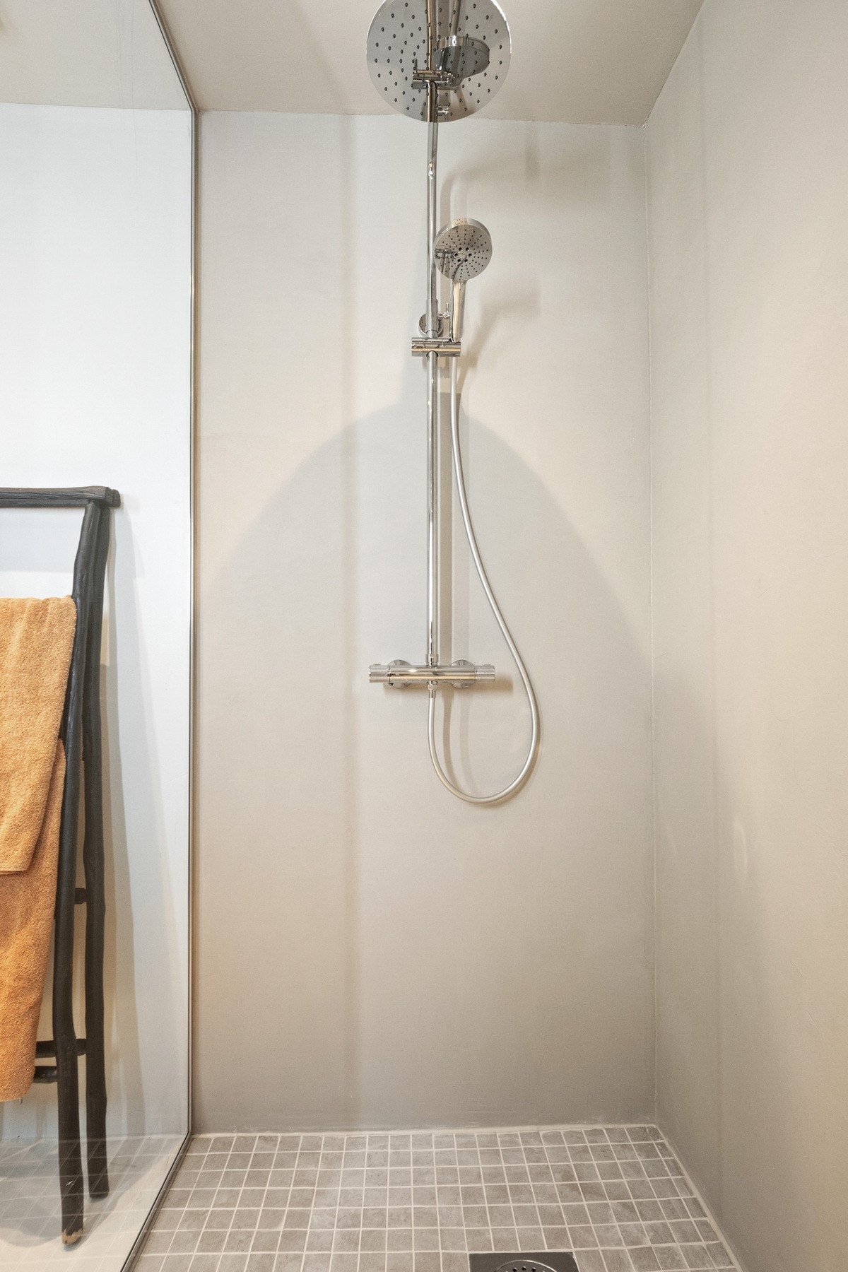 Et nedsenket dusjhjørne er utstyrt med glassvegg, regnfallsdusj og mosaikkfliser på gulvet. Galleribilde