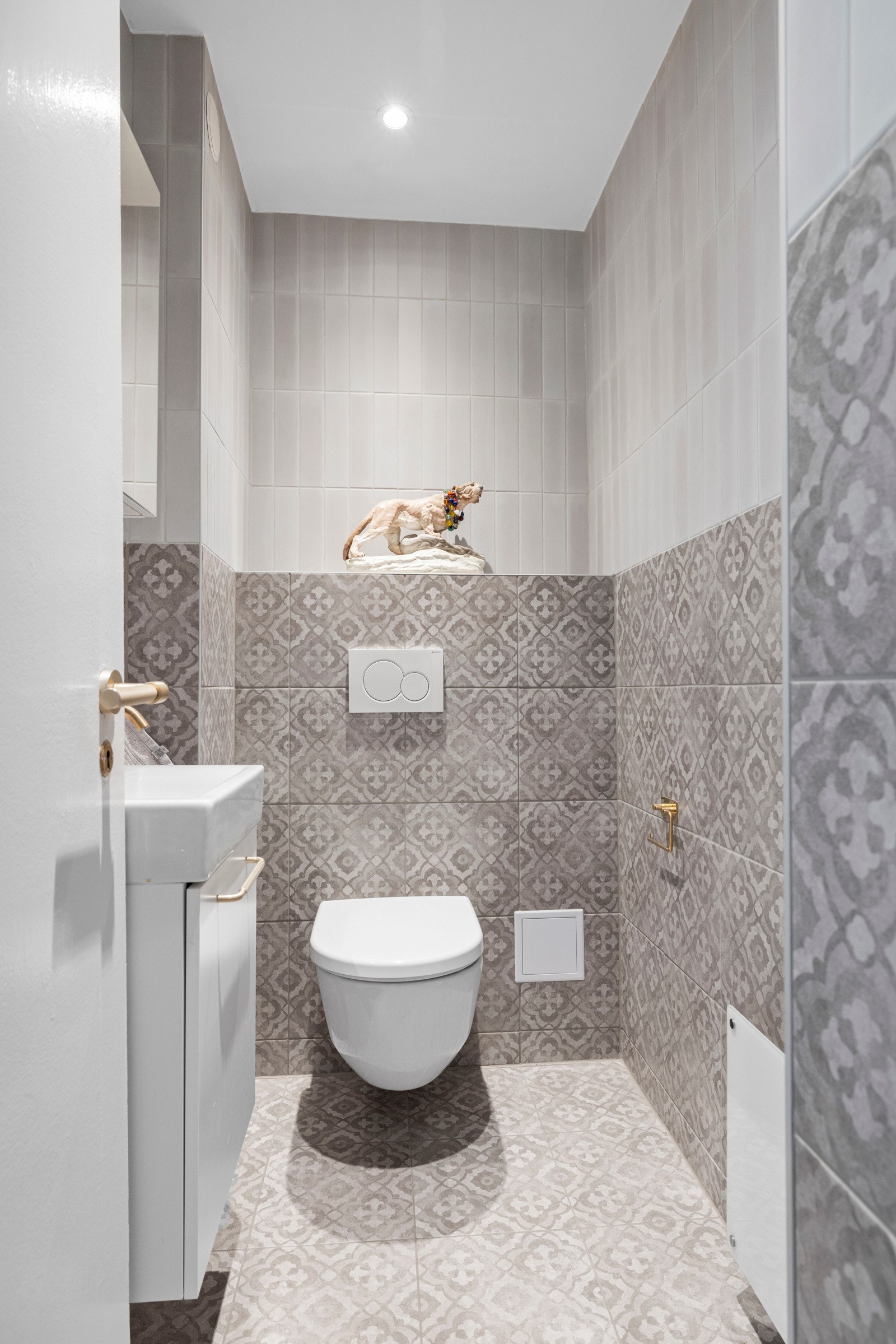 Pent flislagt toalettrom med gulvvarme og panelovn, samt innredet med veggmontert wc og servant. Galleribilde