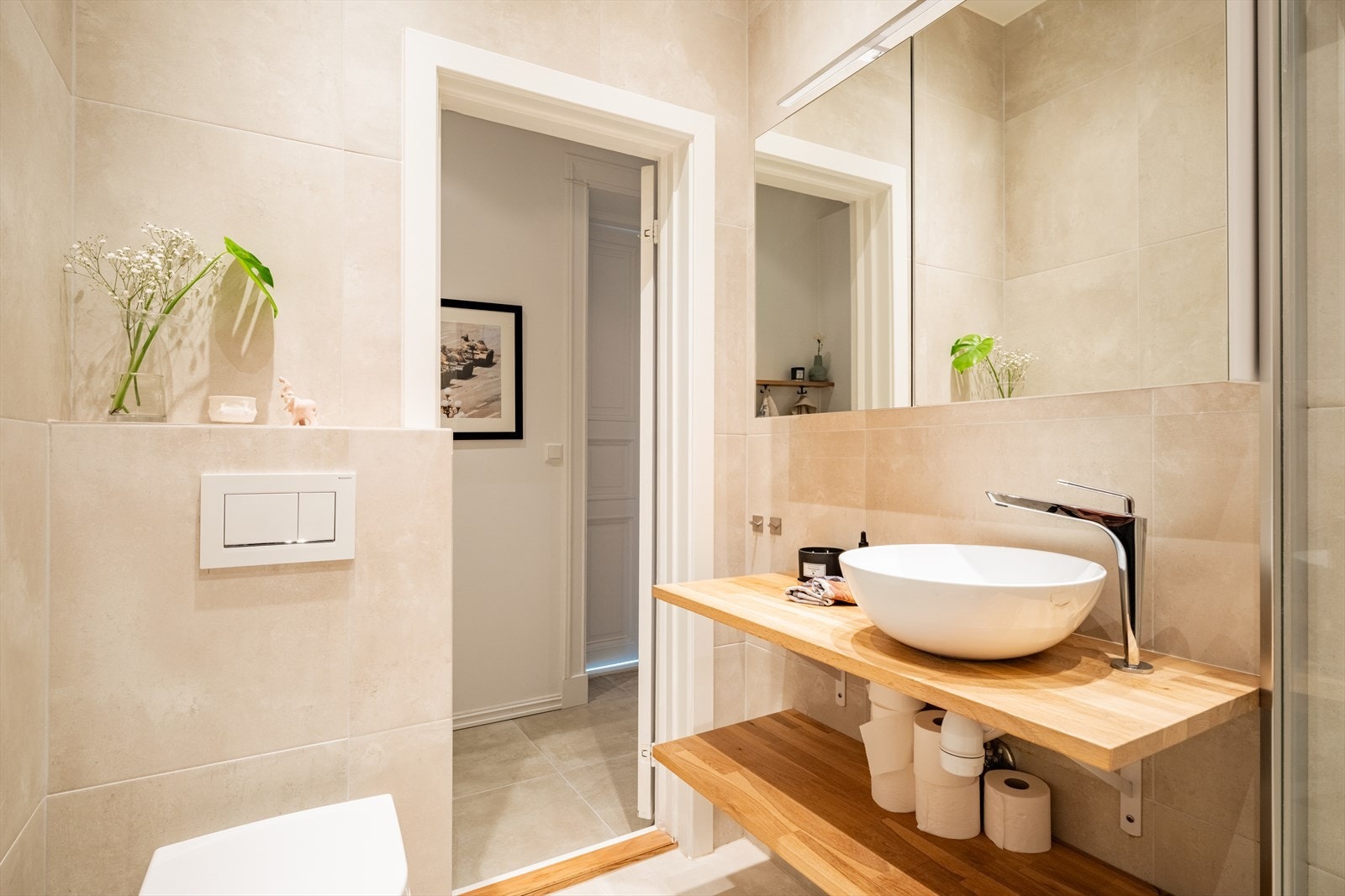 Badet er innredet med benkeplate med servantskål, speilskap med lys, stor dusjsone med hånd- og regnfallsdusj, og veggmontert toalett. Galleribilde