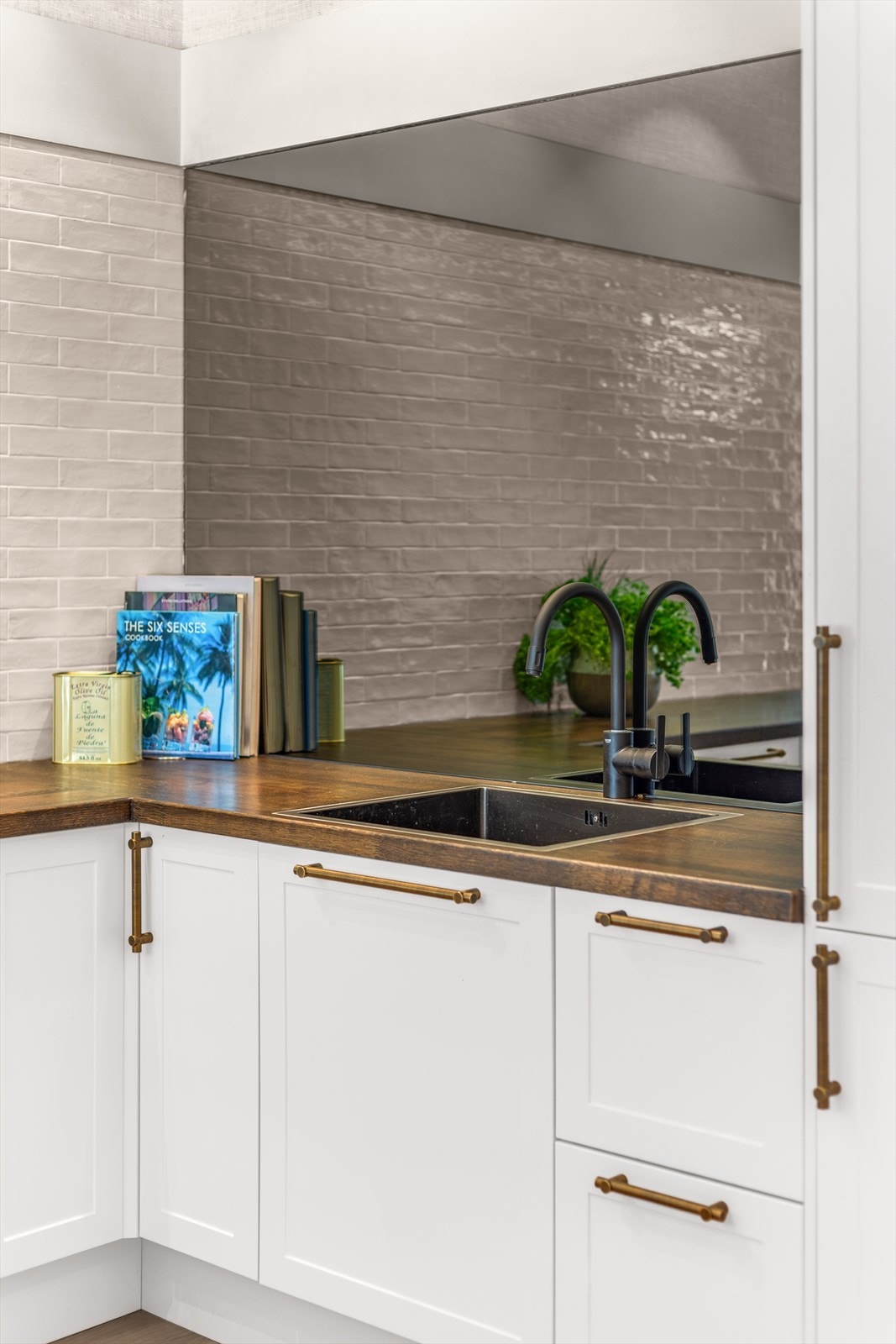 Lekkert sot-farget speil på ene kjøkkenvegg gir et ryddig og fint uttrykk Galleribilde