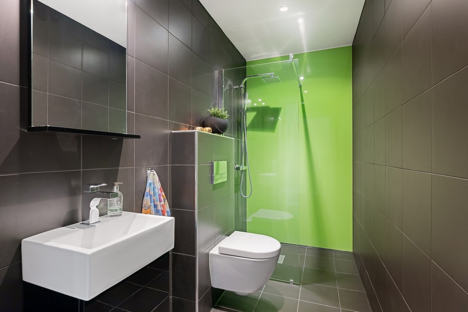 Pent bad fra 2014 med flislagt gulv og vegger, gulvvarme og nedsenket himling med downlights. Vegghengt servantskap med speil og belysning, vegghengt toalett, dusjhjørne med regn- og hånddusj, samt avtrekksventil i himling Galleribilde