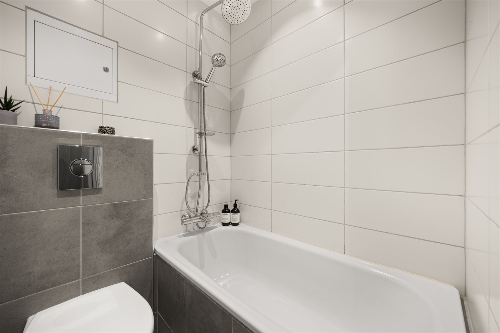 Badet er innredet med servantskap med nedfelt servant, speilskap med belysning, veggmontert toalett med innebygd sisterne og innmurt badekar. Galleribilde