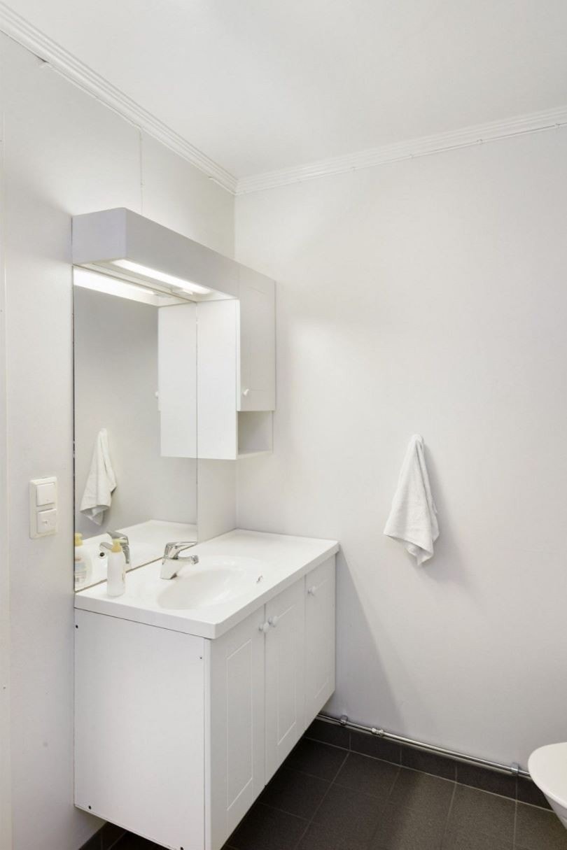 Badet er innredet med innredning med servant, toalett og dusjkabinett. Det er varmekabler i gulvet. Galleribilde