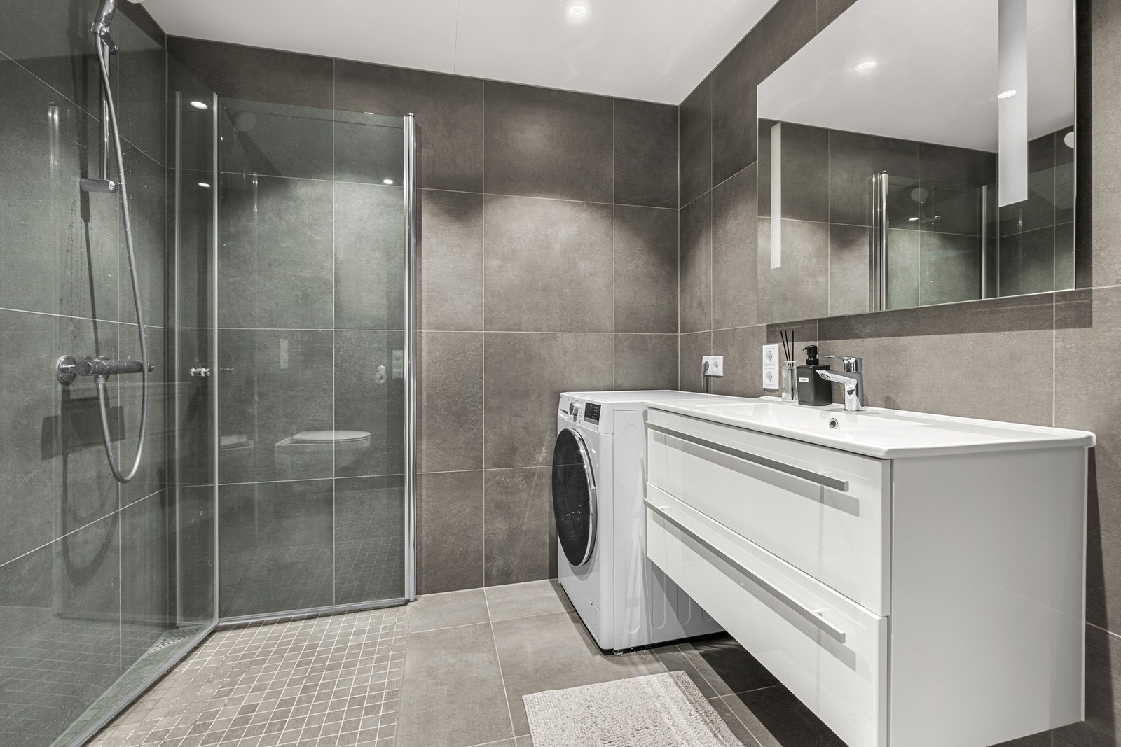 Delikat og moderne bad med god plass til vaskemaskin Galleribilde