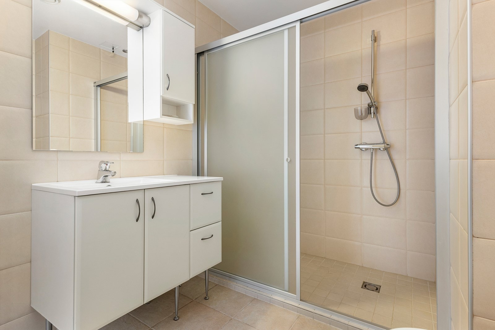 I rommet finner du en stor dusjnisje, en klassisk baderomsinnredning, gulvmontert toalett og opplegg for vaskemaskin. Galleribilde