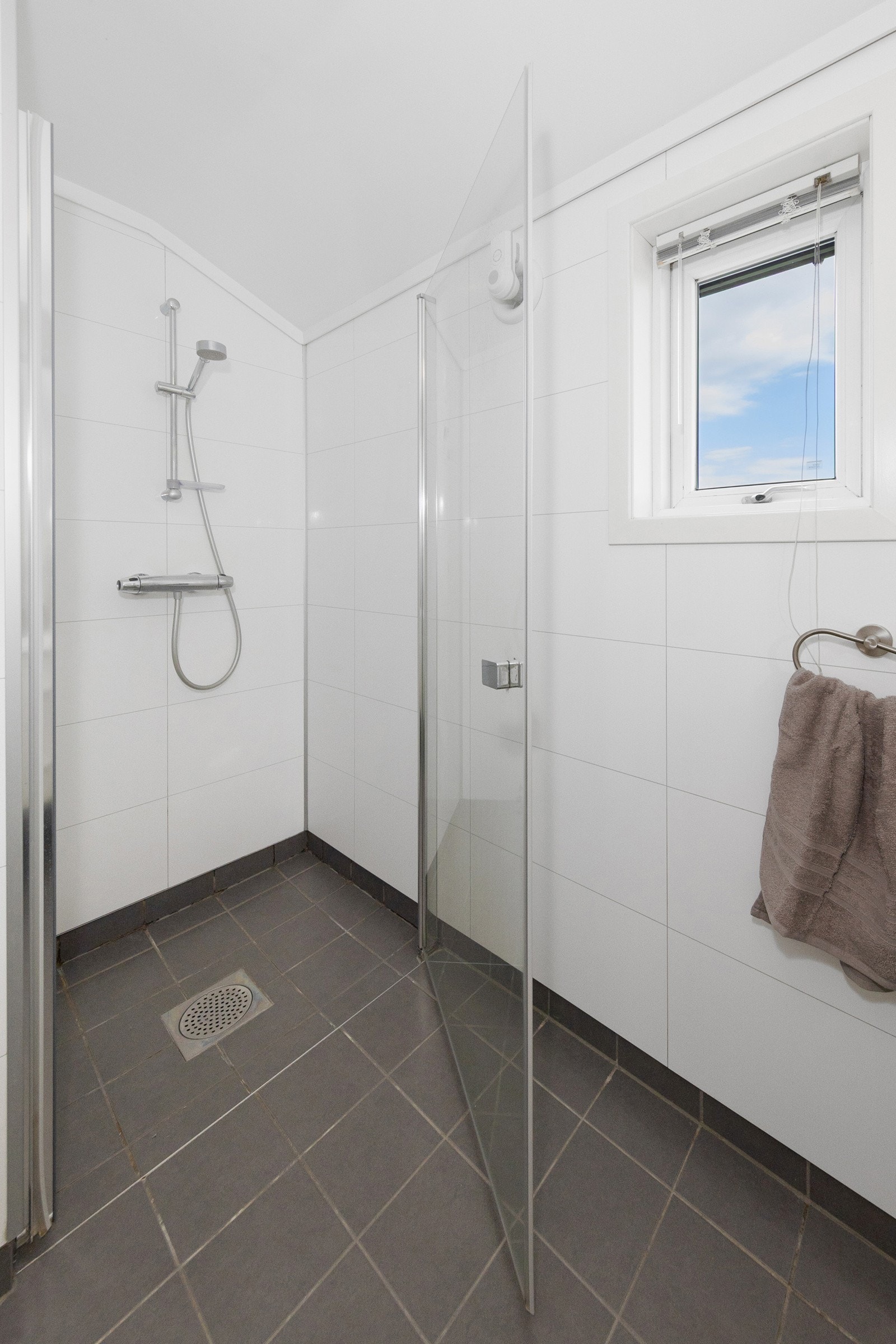 Servant i innredning, speil med lys, vegghengt toalett og dusjnisje med glassdør Galleribilde