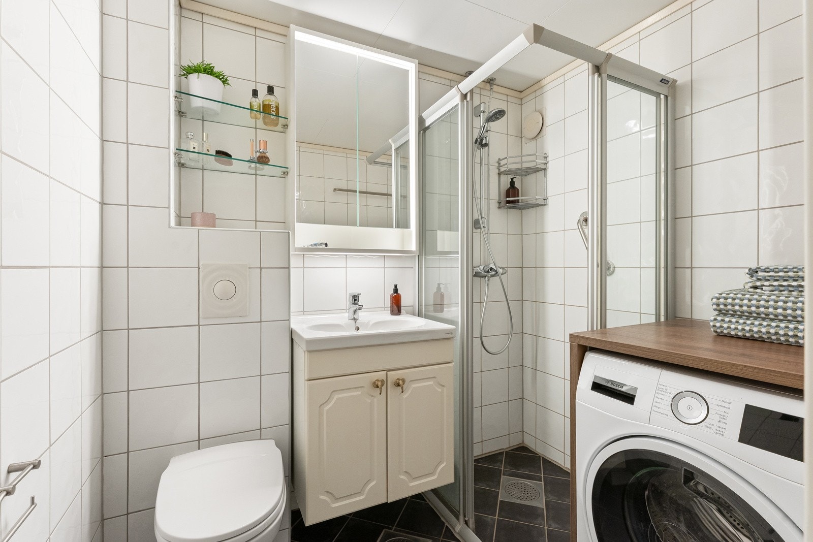 Badet er funksjonelt innredet med smart plassutnyttelse og plass til vaskemaskin. Galleribilde