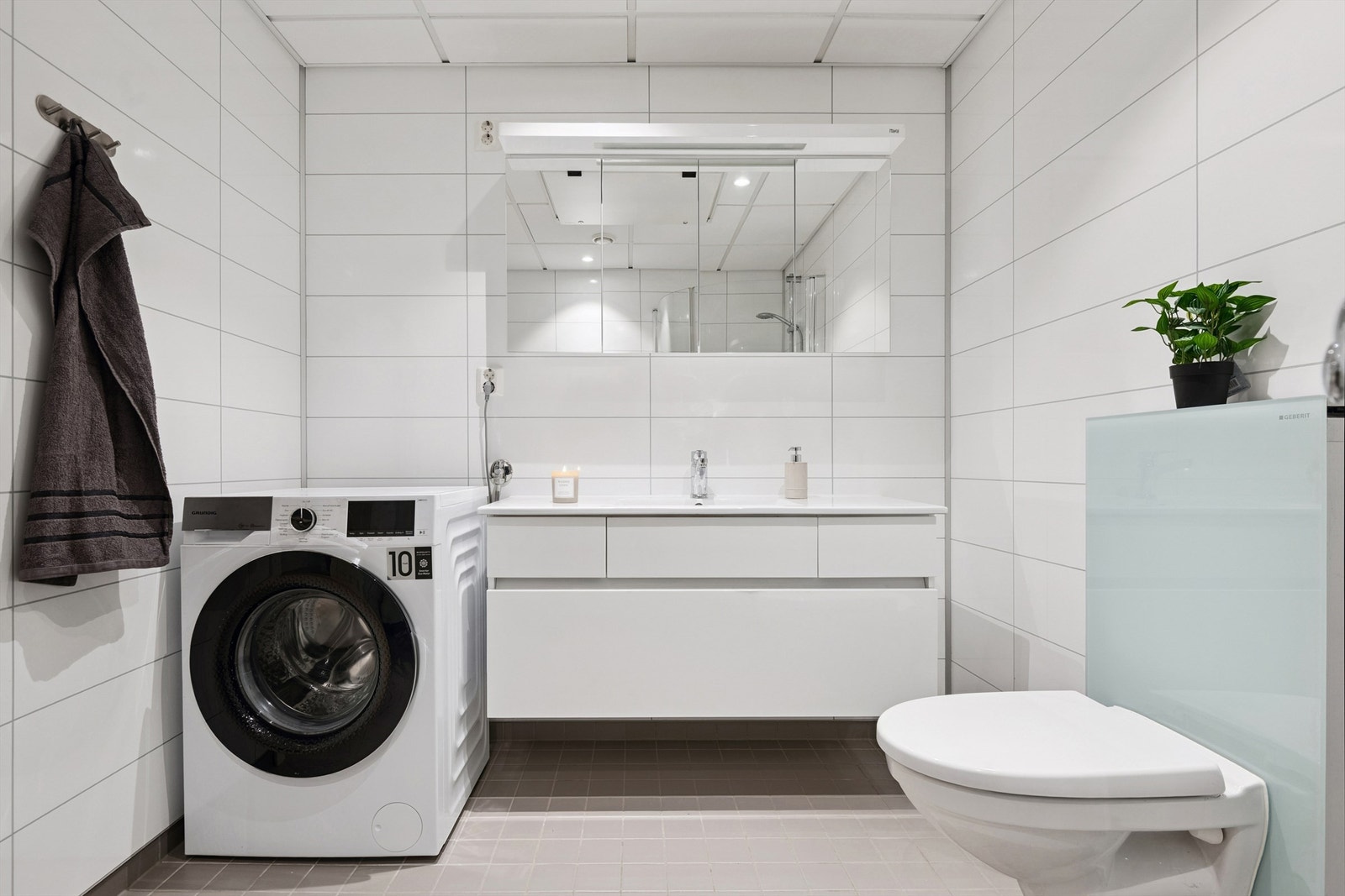 Innredningen inkluderer servantmøbel med god oppbevaring og praktisk opplegg for vaskemaskin. Galleribilde