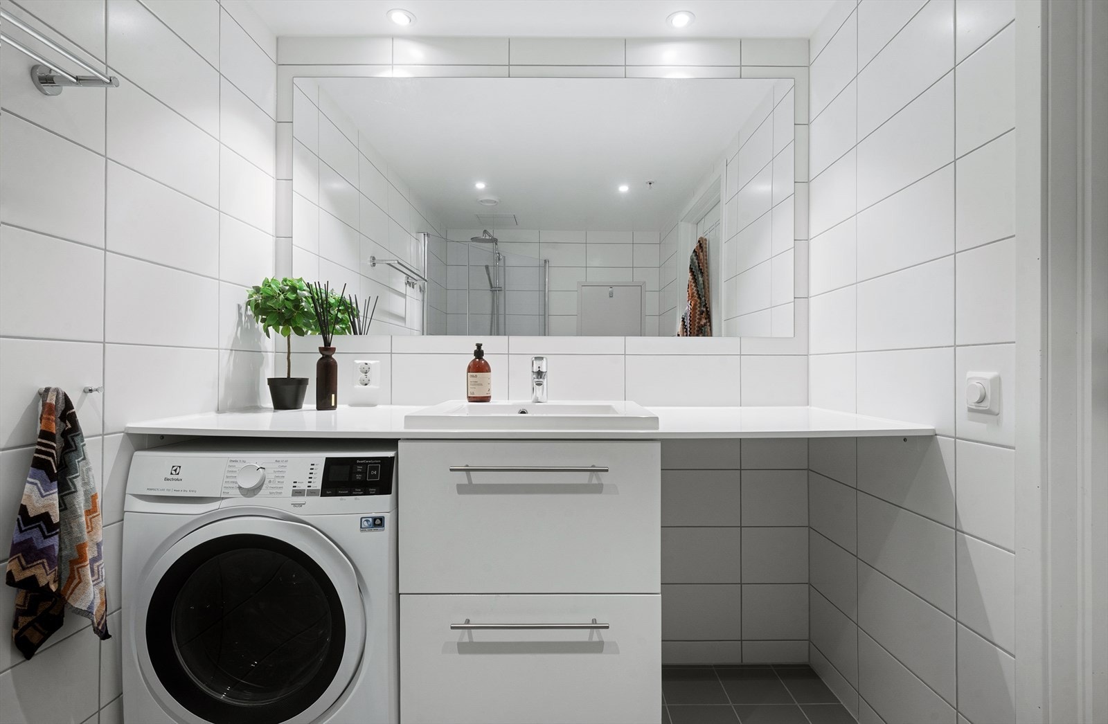 Badet er utstyrt med vegghengt toalett, servantinnredning , ettgreps blandebatteri, dusj med dører i glass, plass og opplegg for vaskemaskin, samt vannbåren gulvvarme. Galleribilde