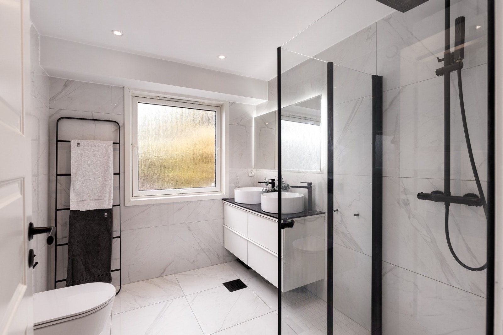 Badet, oppgradert i 2021, fremstår som både funksjonelt og elegant - med fliser på gulv og vegger, varmekabler og downlights i himlingen. Galleribilde