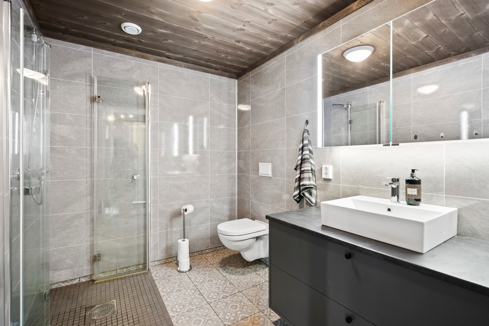 Moderne og delikat bad med flislagt gulv, stort dusjhjørne, vegghengt toalett og flott servantinnredning. Galleribilde