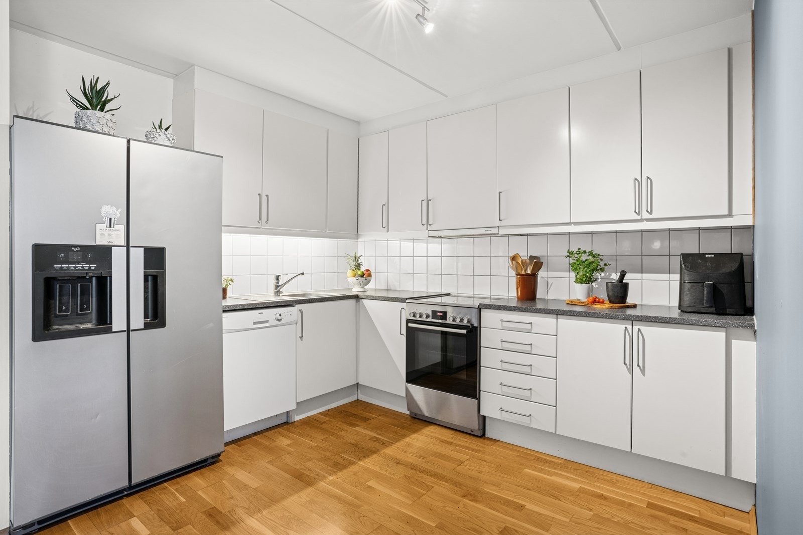 Kjøkkenet har tidløs innredning med hvite, glatte fronter og laminat benkeplate i en grå nyanse. Galleribilde