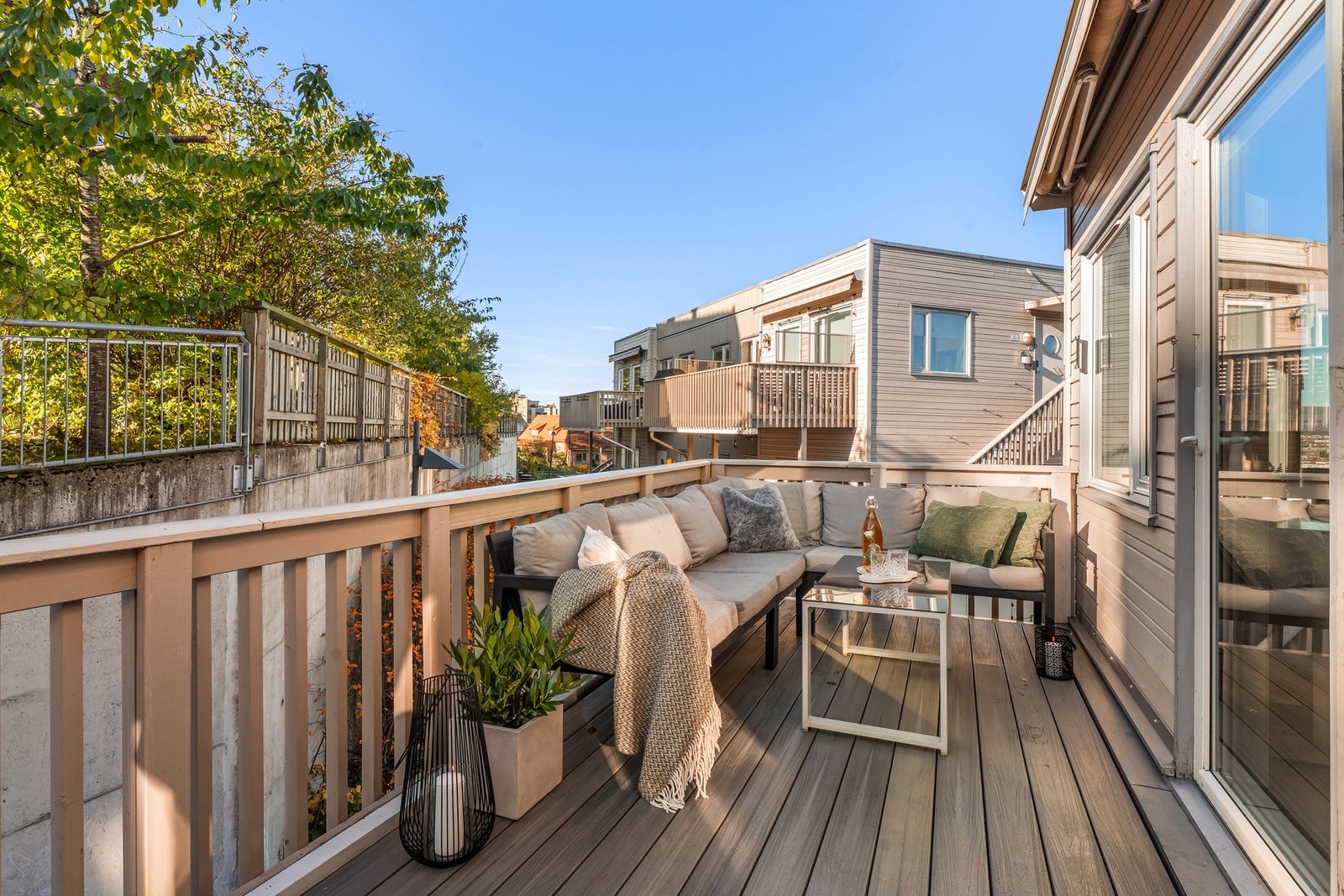 Balkongen har dekke og rekkverk i tre, og på husveggen er det montert utestikk og en bred, motorisert markise. Galleribilde