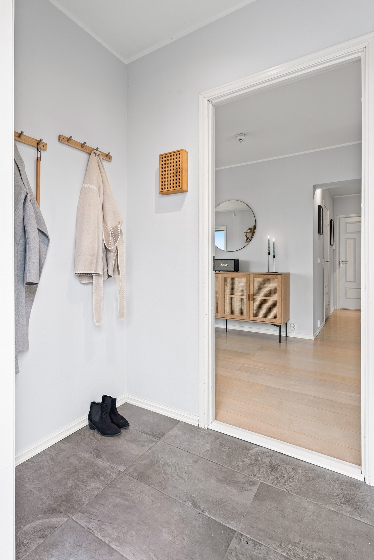 Pen entré med lysmalte vegger og store, grå fliser på gulvet. Galleribilde