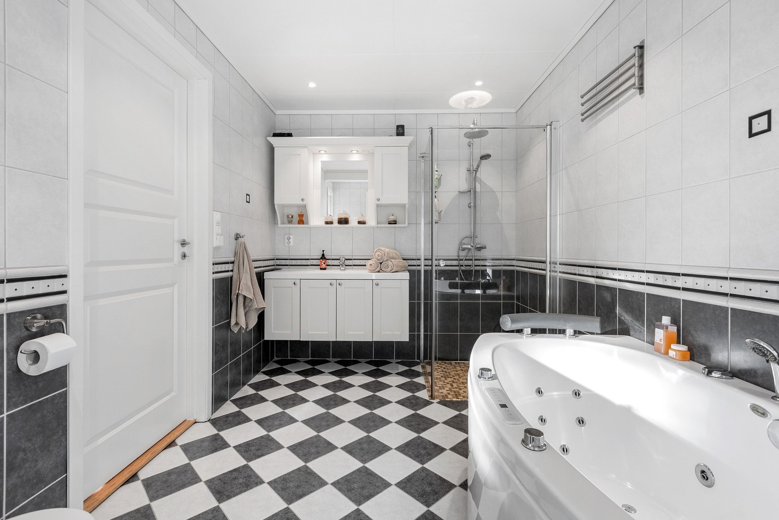 Flislagt bad med varmekabler, innredning, dusjhjørne og boblebadekar. Toalett. Galleribilde