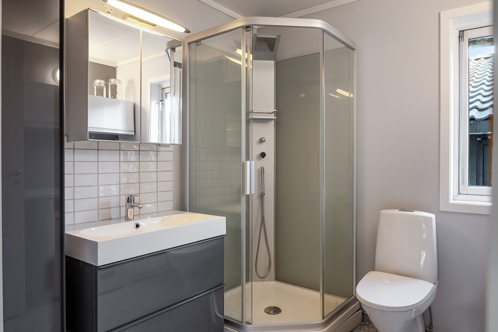 Lyst baderom med våtromsbelegg på gulv, elektriske varmekabler i gulv, lysmalte plater på veggene og mekanisk avtrekk. Galleribilde