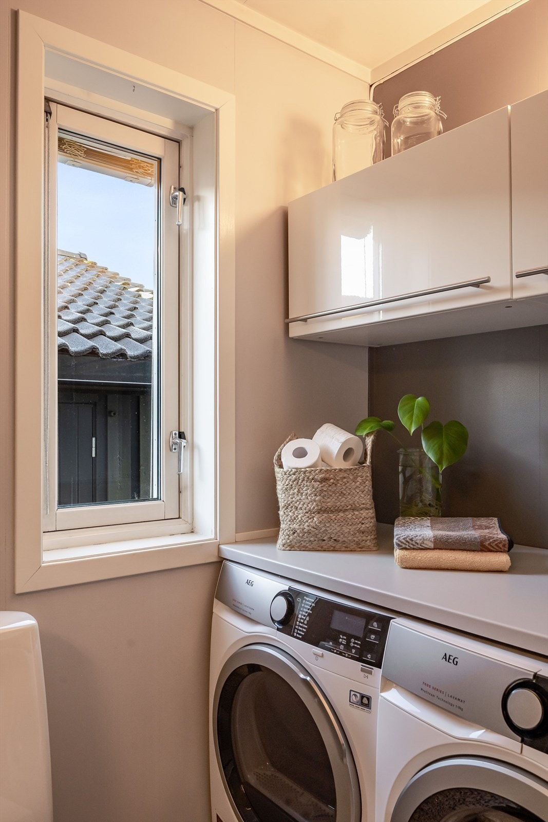 Her har du plass og opplegg for både vaskemaskin og tørketrommel under benkeplate, samt vegghengte skap for oppbevaring over. Galleribilde