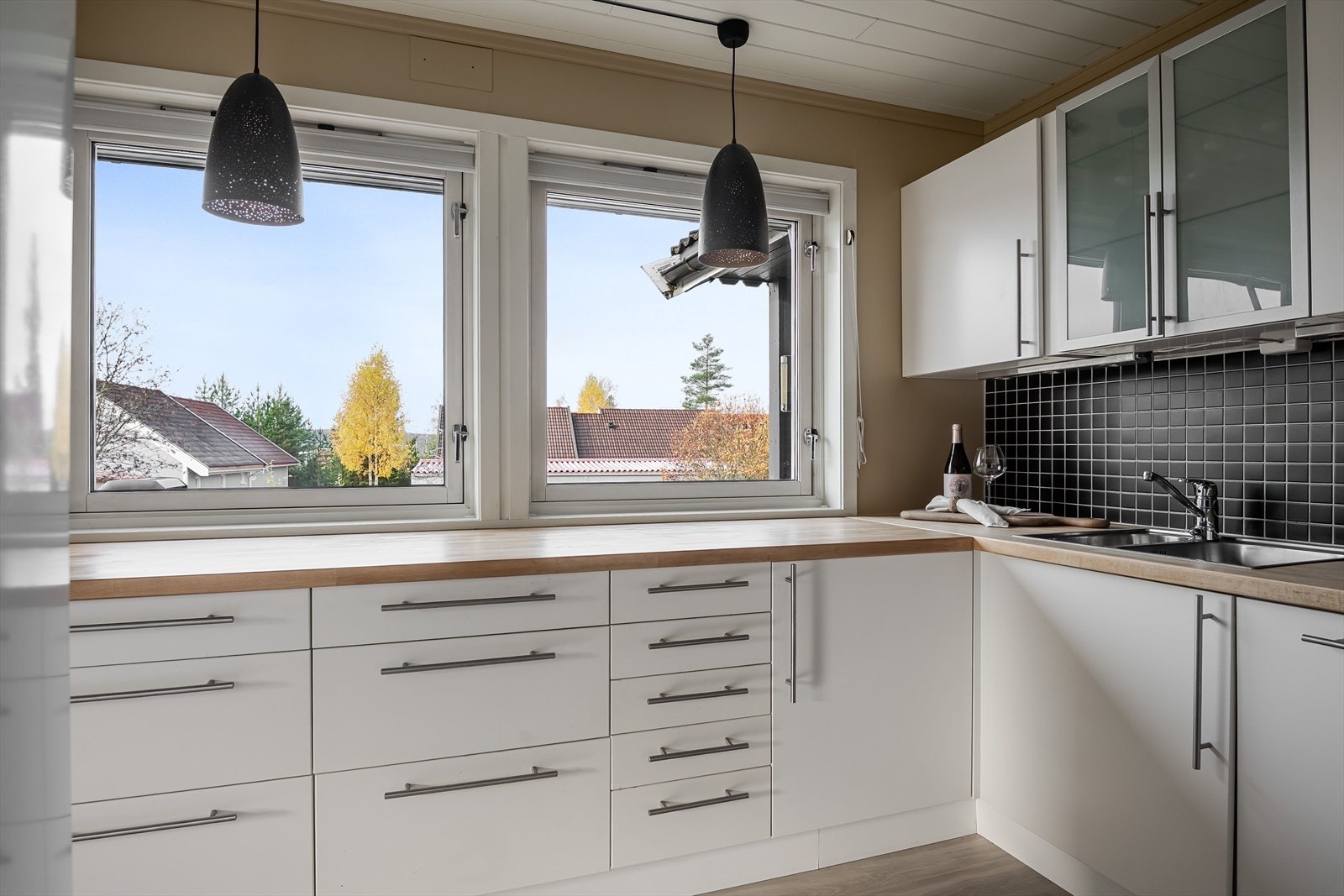 Kjøkkenet har en praktisk utforming som sørger for god skap- og benkeplass. To store vinduer slipper inn fint naturlig lys og gjør dette til et trivelig og velfungerende kjøkken! Galleribilde