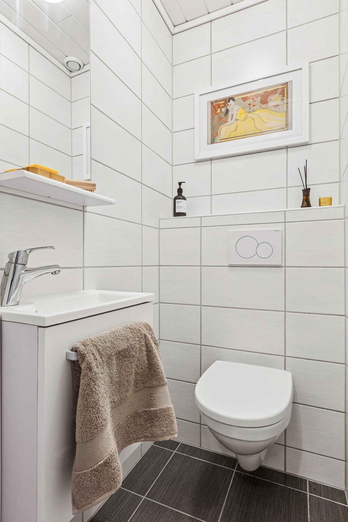 Flislagt toalettrom med vegghengt toalett og servant. Galleribilde