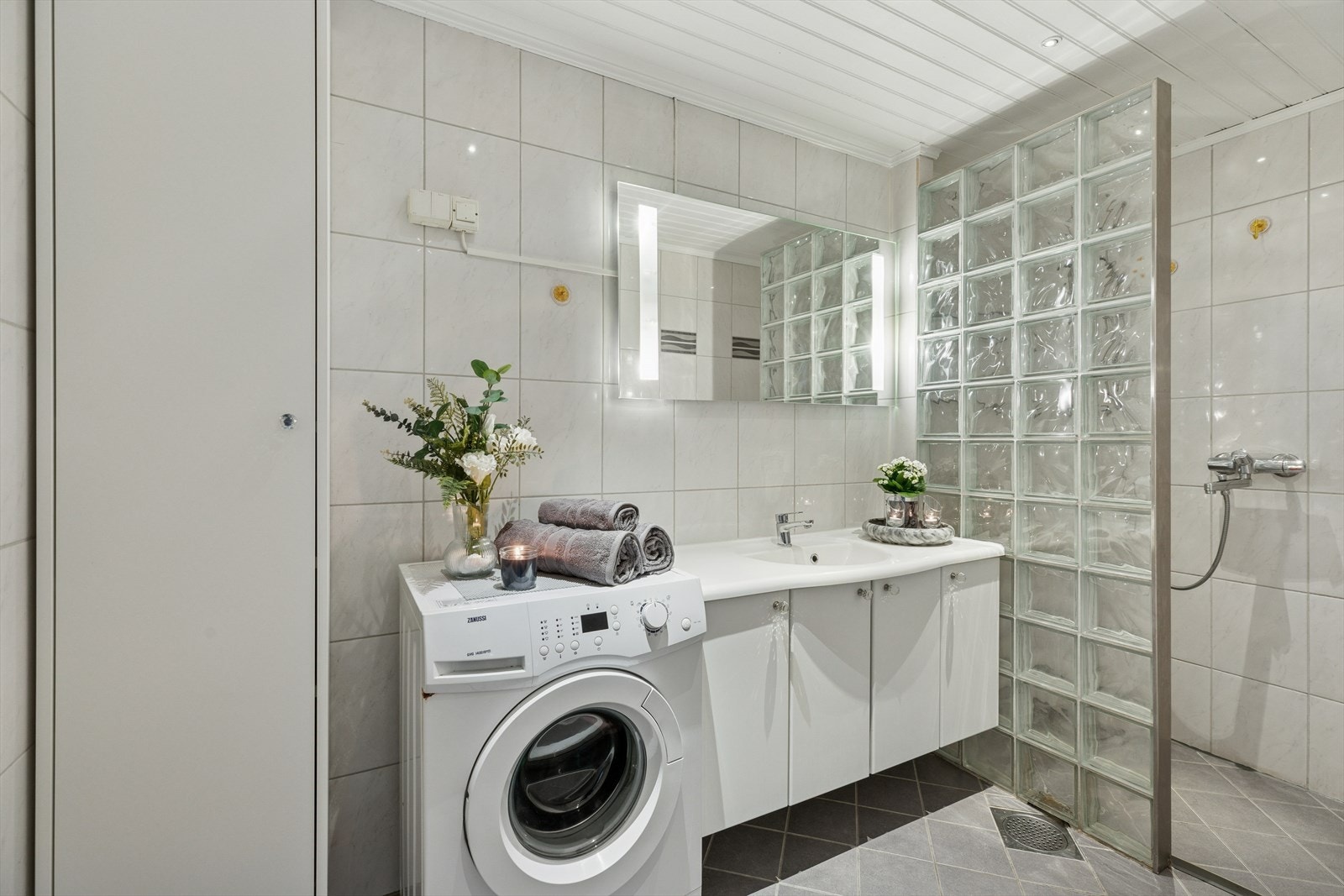 Badet er utstyrt med innredning med nedfelt servant, toalett, dusjvegger/hjørne og opplegg for vaskemaskin. Galleribilde