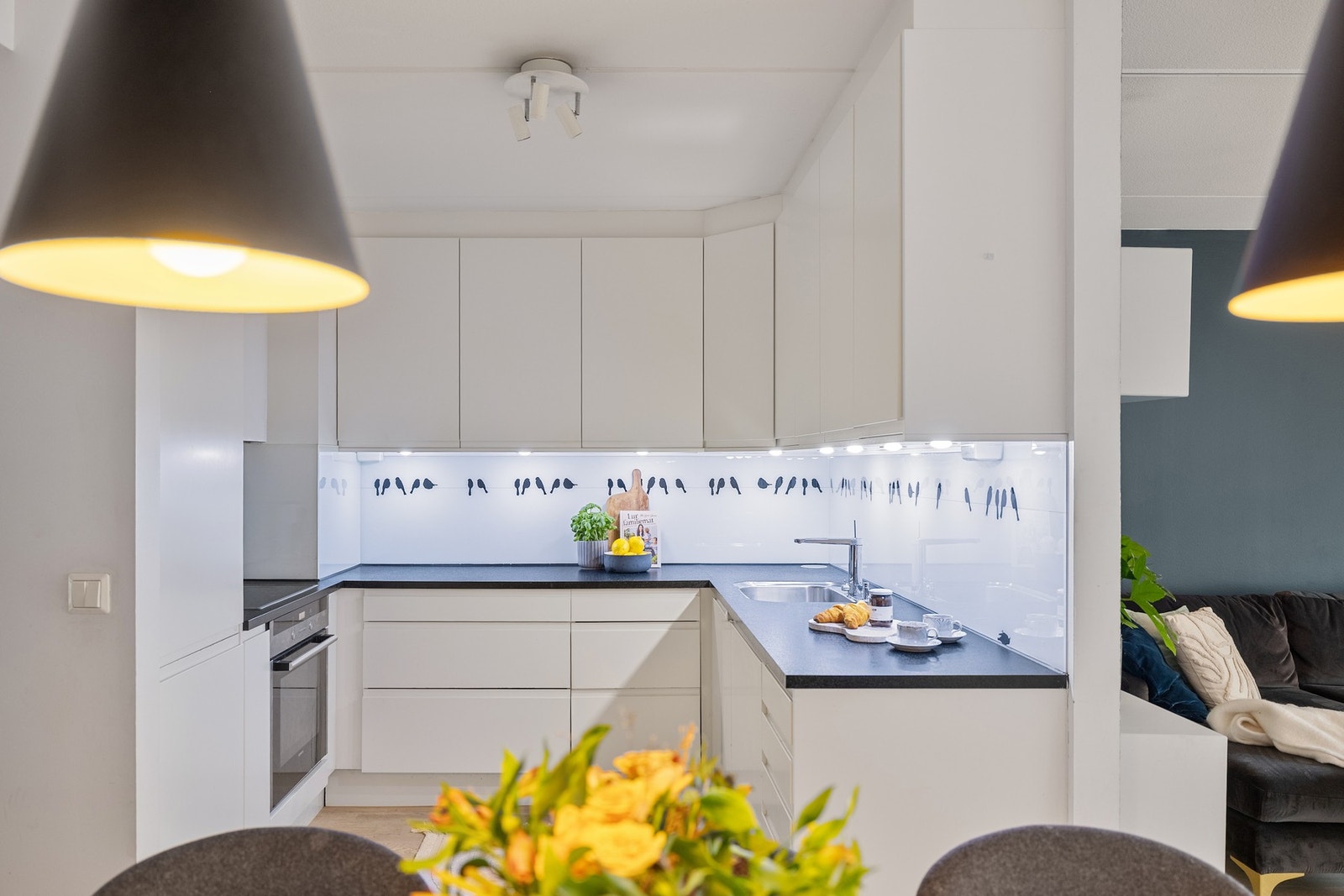 Moderne kjøkkeninnredning med hvite glatte fronter m/ integrerte grep. Laminat benkeplate med underlimt oppvaskkum. Galleribilde
