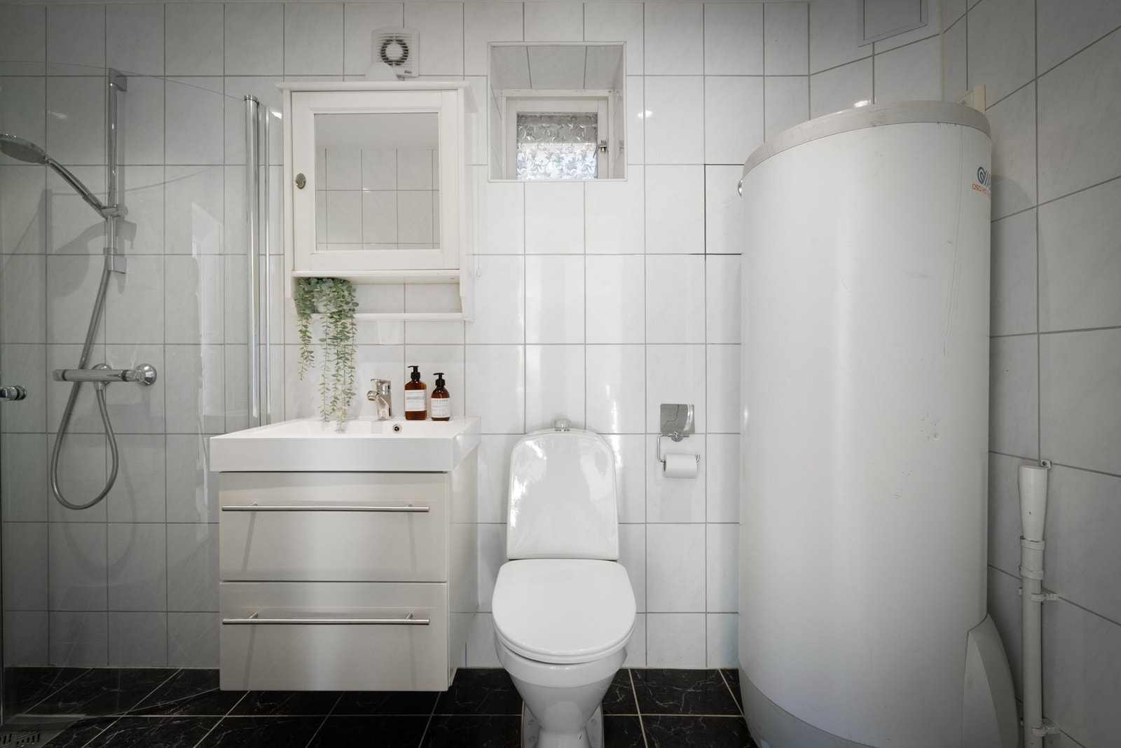 Badet er utstyrt med foldedører i dusj, veggtoalett og baderomsinnredning med heldekkende servant samt belyst speil, og har opplegg for vaskemaskin. Galleribilde