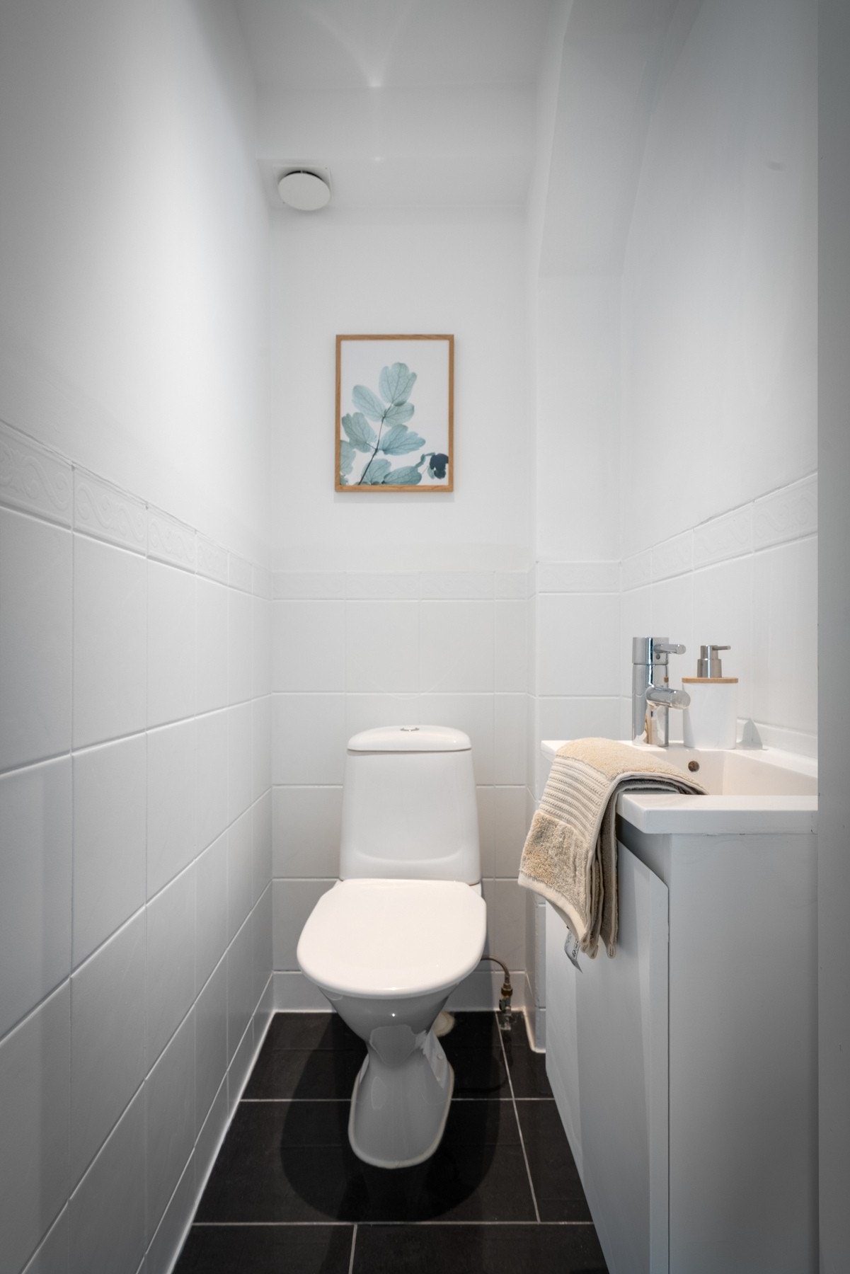 Helfliset toalettrom, innredet med toalett og servant med enkel baderomsinnredning. Galleribilde