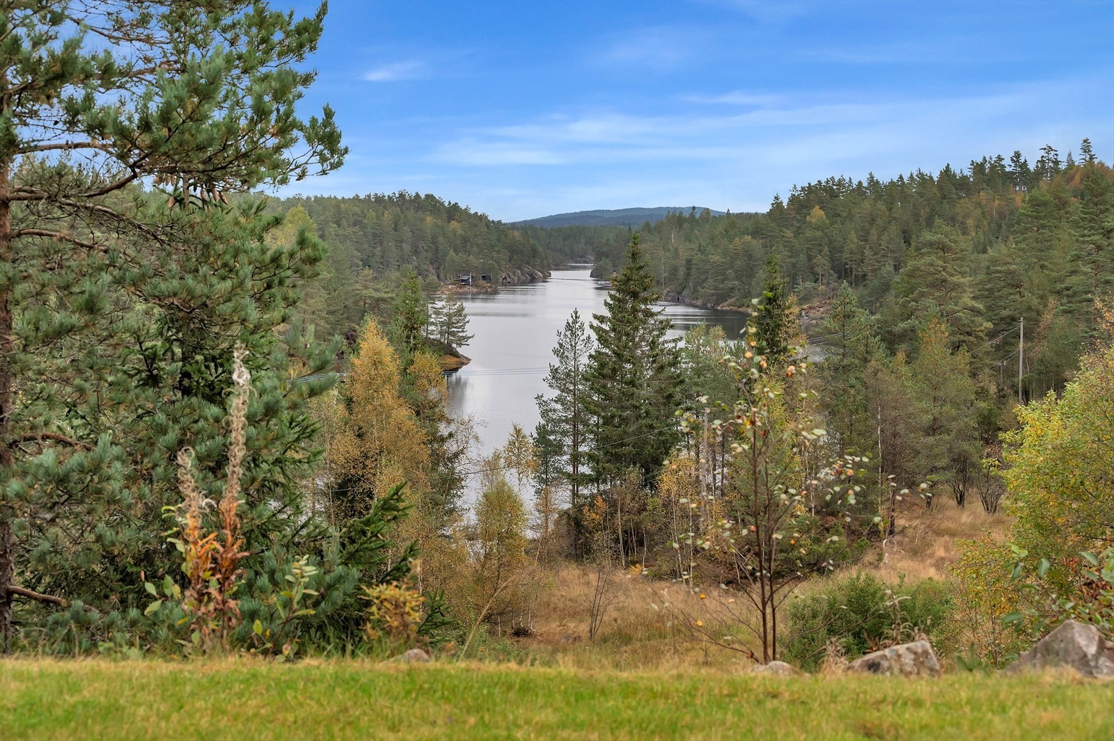 Fra eiendommen har man utsikt mot skogkledde åser og et nærliggende vann, som gir en fredelig og naturnær atmosfære. Galleribilde