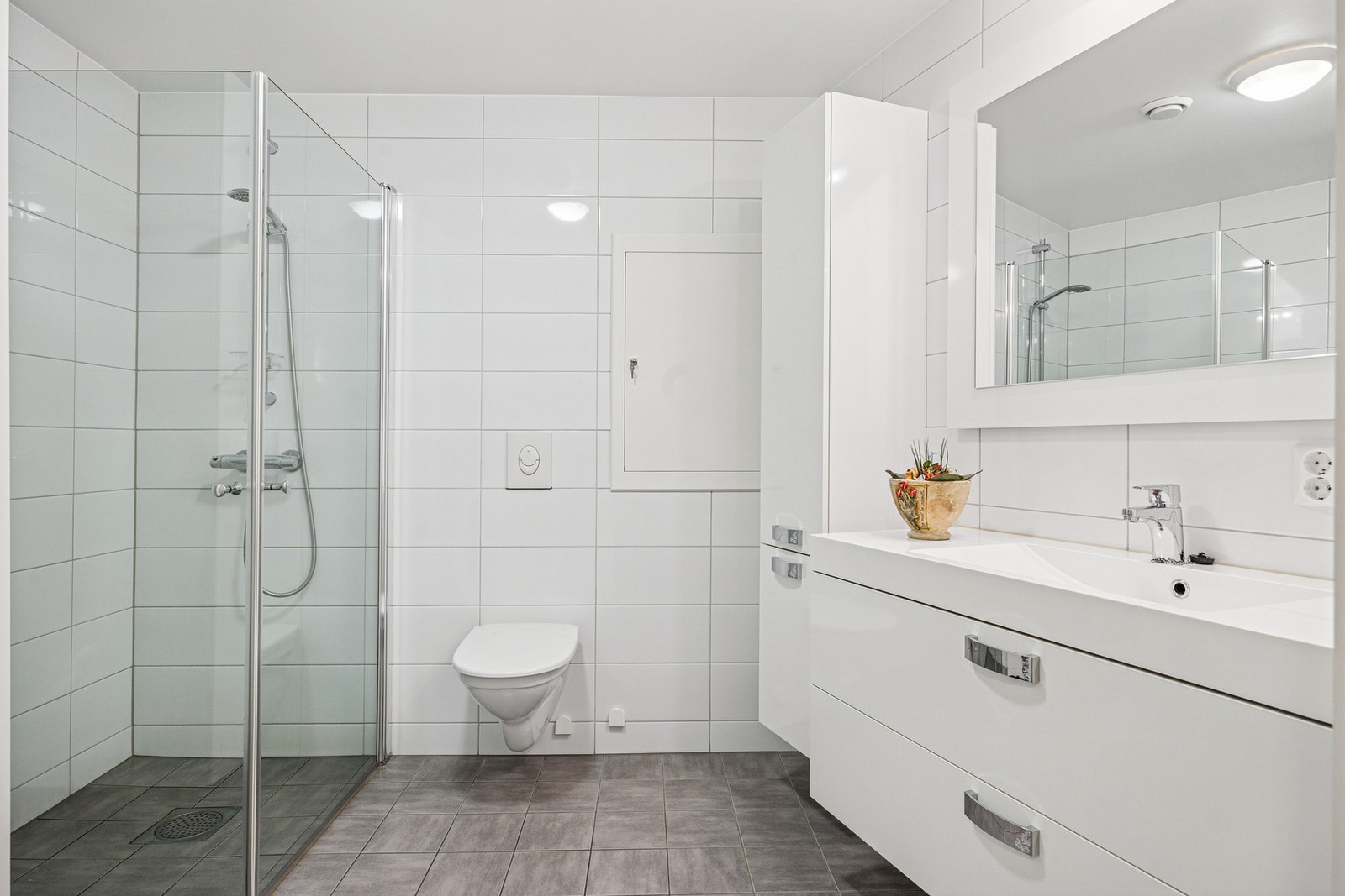 Leiligheten har et delikat og moderne baderom fra byggeår med flislagte gulv og vegger, samt gulvvarme for ekstra komfort. Galleribilde