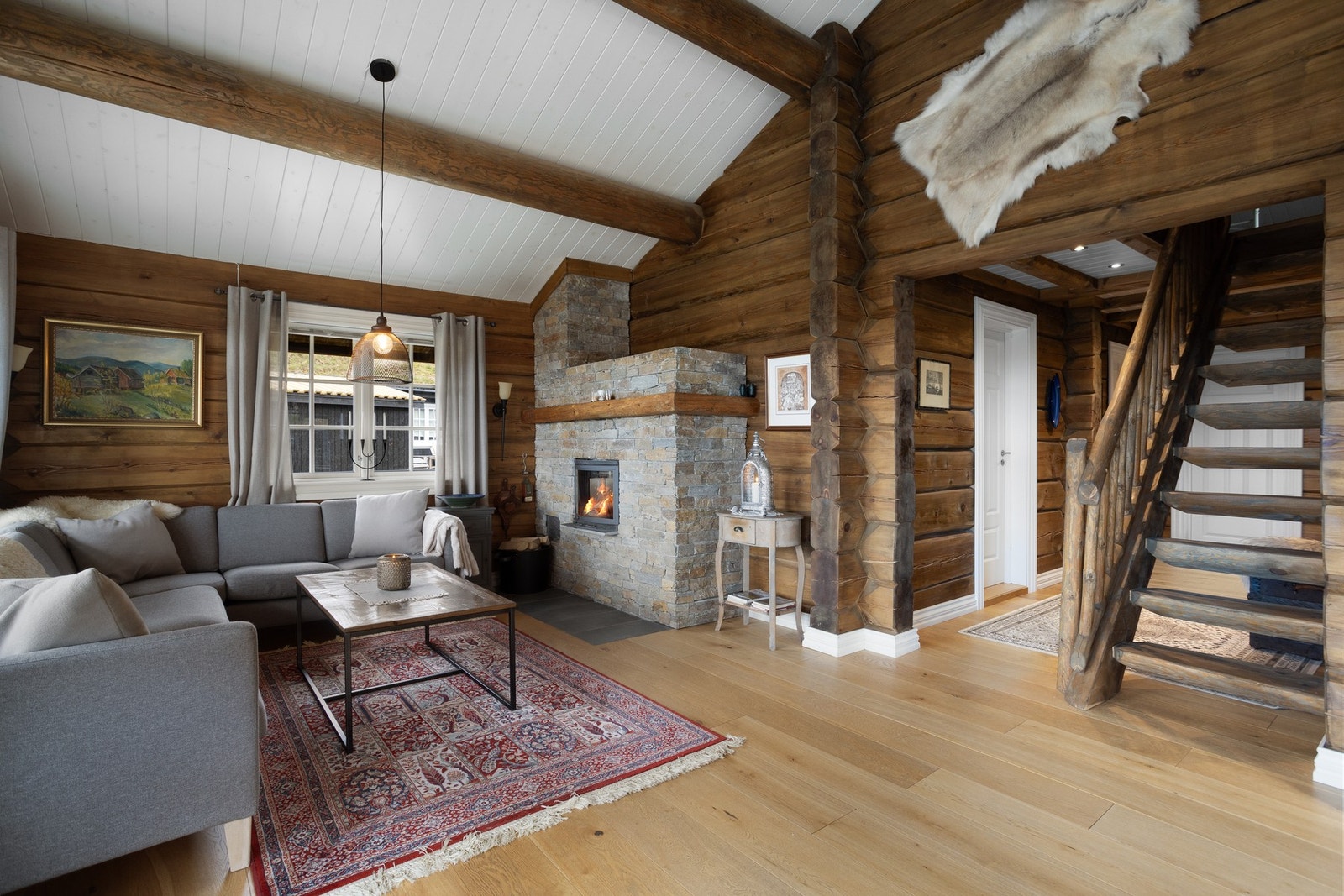 Hytta har peis og varmepumpe med appstyring. Peisen passer perfekt på fjellhytta. Her kan man nyte synet av flammene fra sofakroken Galleribilde