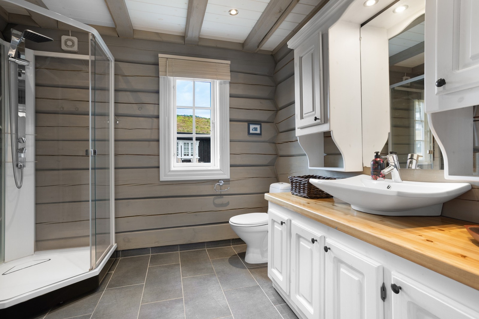 Baderom I i 1.etasje. Baderommet inneholder toalett, dusjkabinett, innredning med servant og opplegg til vaskemaskin Galleribilde