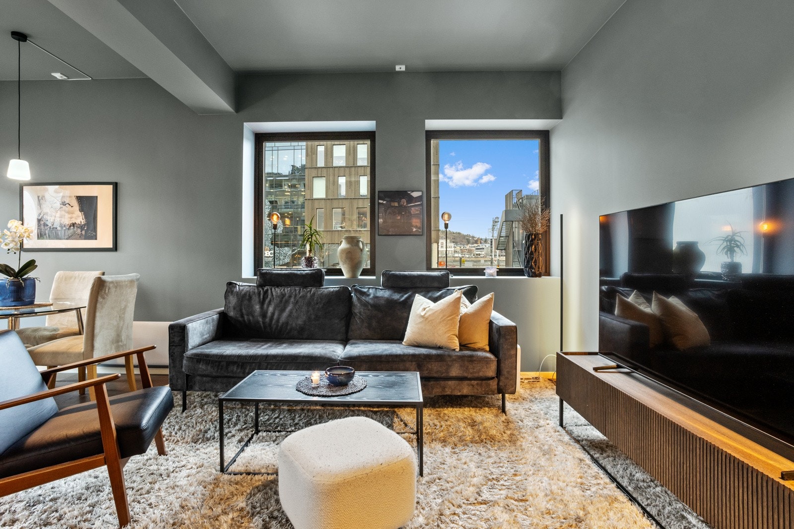 Stilfull stue med store vindusflater som gir rikelig lysinnslipp og utsyn. En innbydende arena for både hverdagskos og sosiale lag. Galleribilde