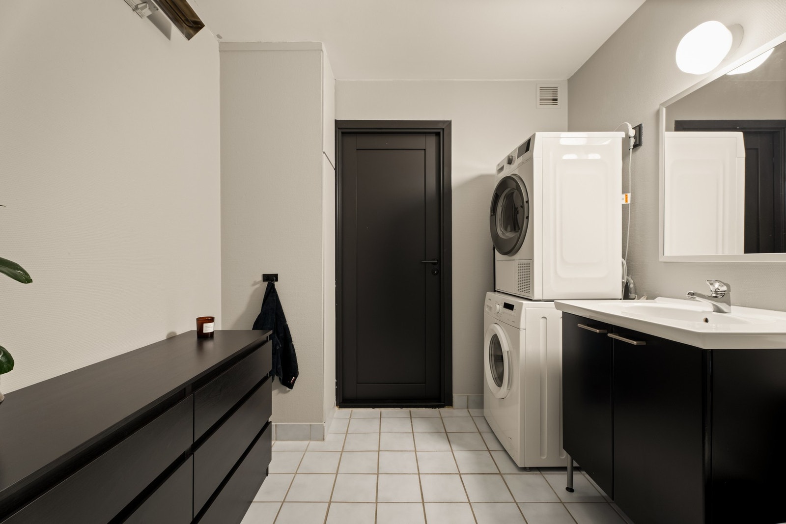 Baderomsinnredningen har sorte fronter og består av en heldekkende servant på en skapseksjon, et veggskap og et stort speil med belysning. Galleribilde