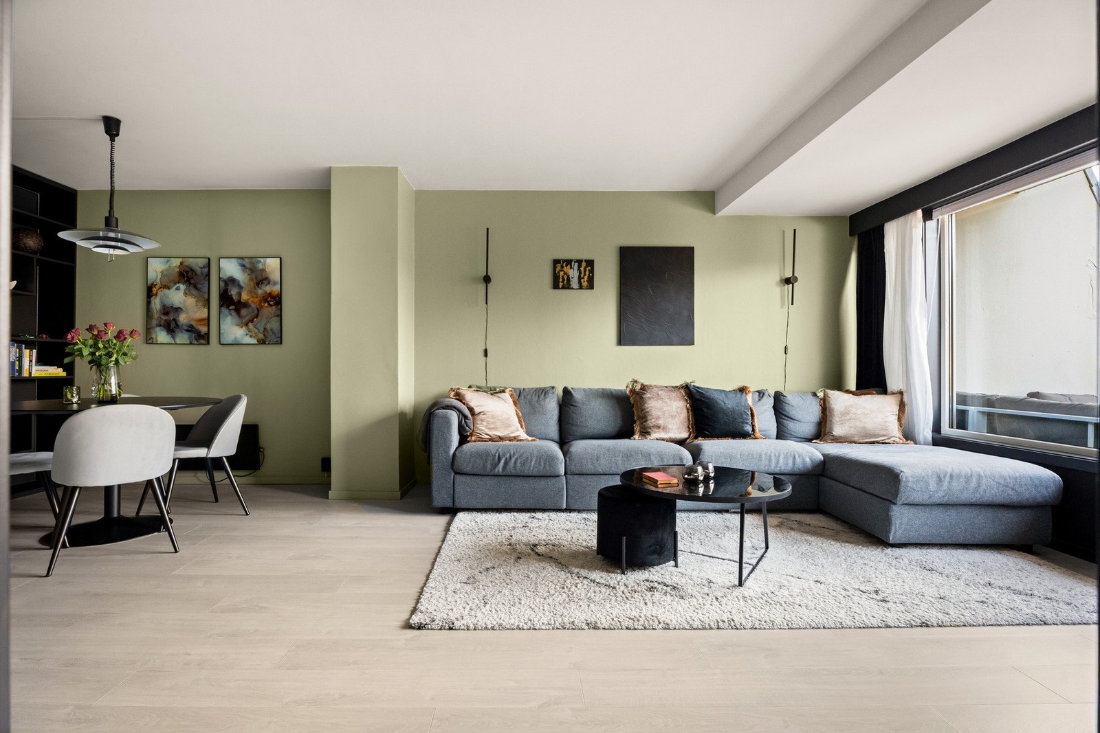 sofagruppe, godstol og tv-/mediastasjon, og i nærheten av kjøkkenet er det plass til spisebord. Veggene er malt opp i en dus, delikat grønntone og rommet har lys, enstavs laminat på gulvet. Galleribilde